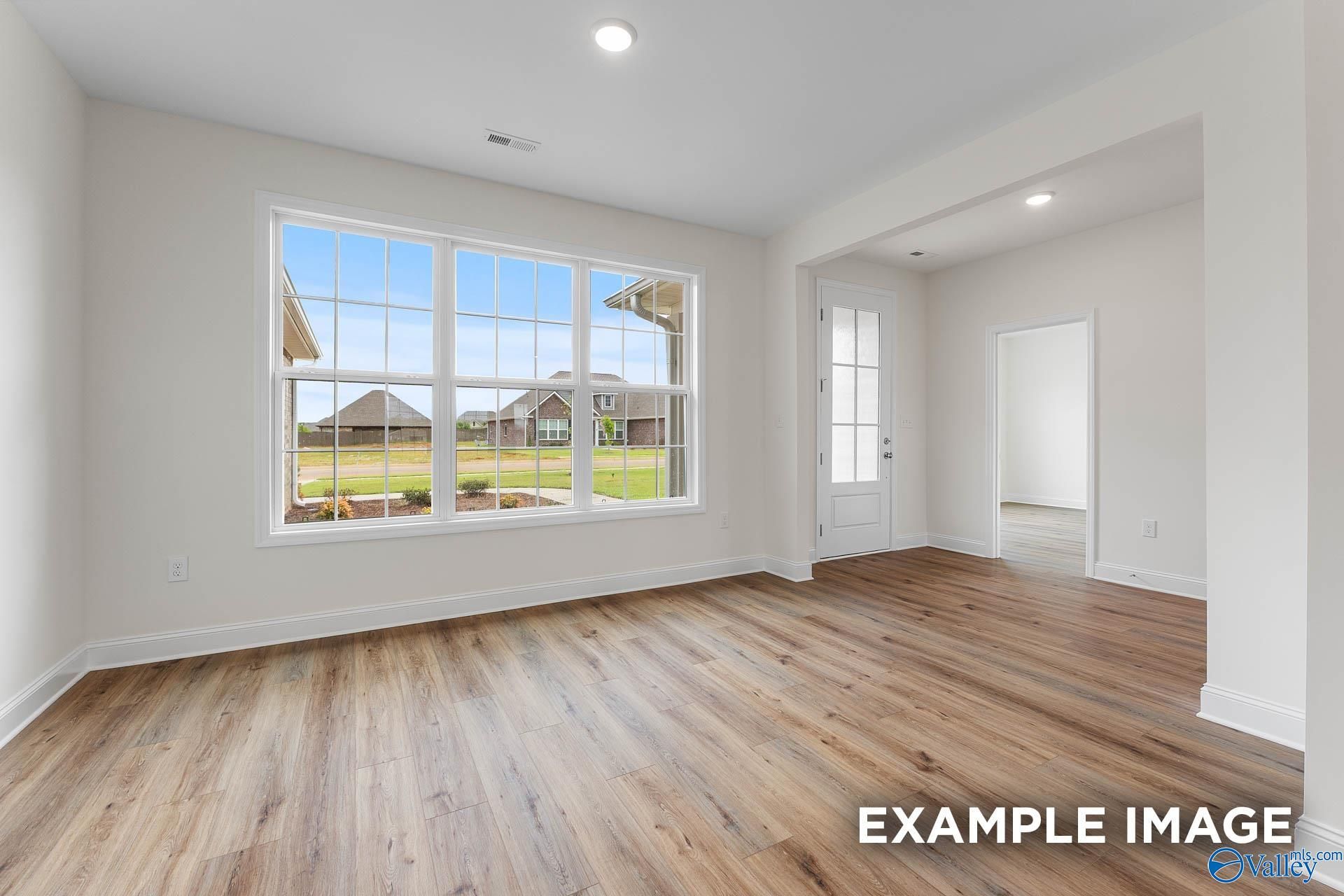 Bright living room with hardwood floors, large windows overlooking backyard in Davidson Homes The Emory, Toney, Alabama