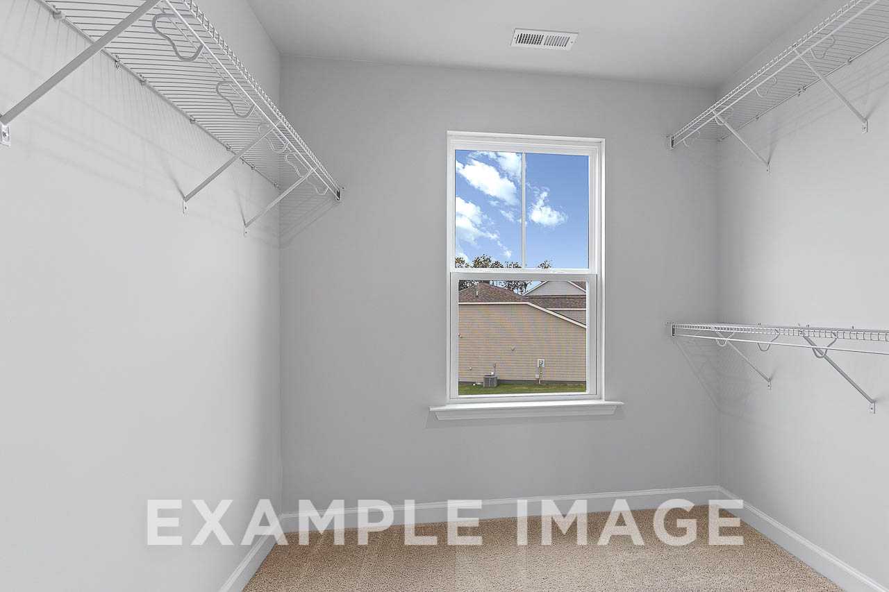 Spacious master walk-in closet in The Willow C with wire shelving, neutral tones, and sunny window view