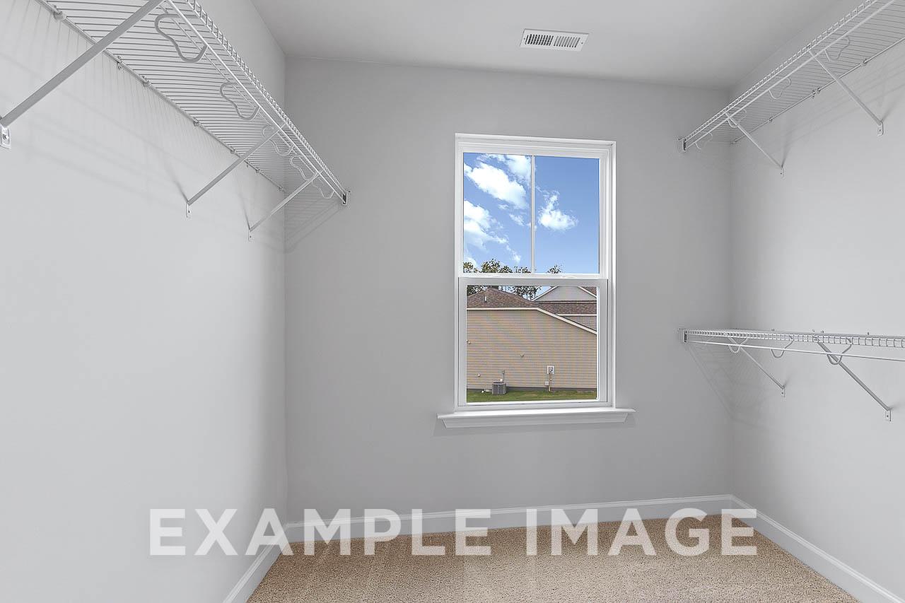 Spacious master walk-in closet in The Willow C with wire shelving, neutral tones, and sunny window view