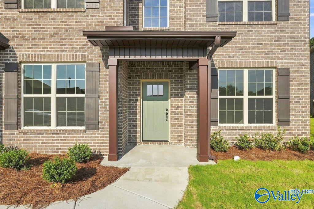 Brick facade and sage green front door of a 2-story Davidson Homes Madison A floor plan in Cain Park, Hartselle, Alabama.