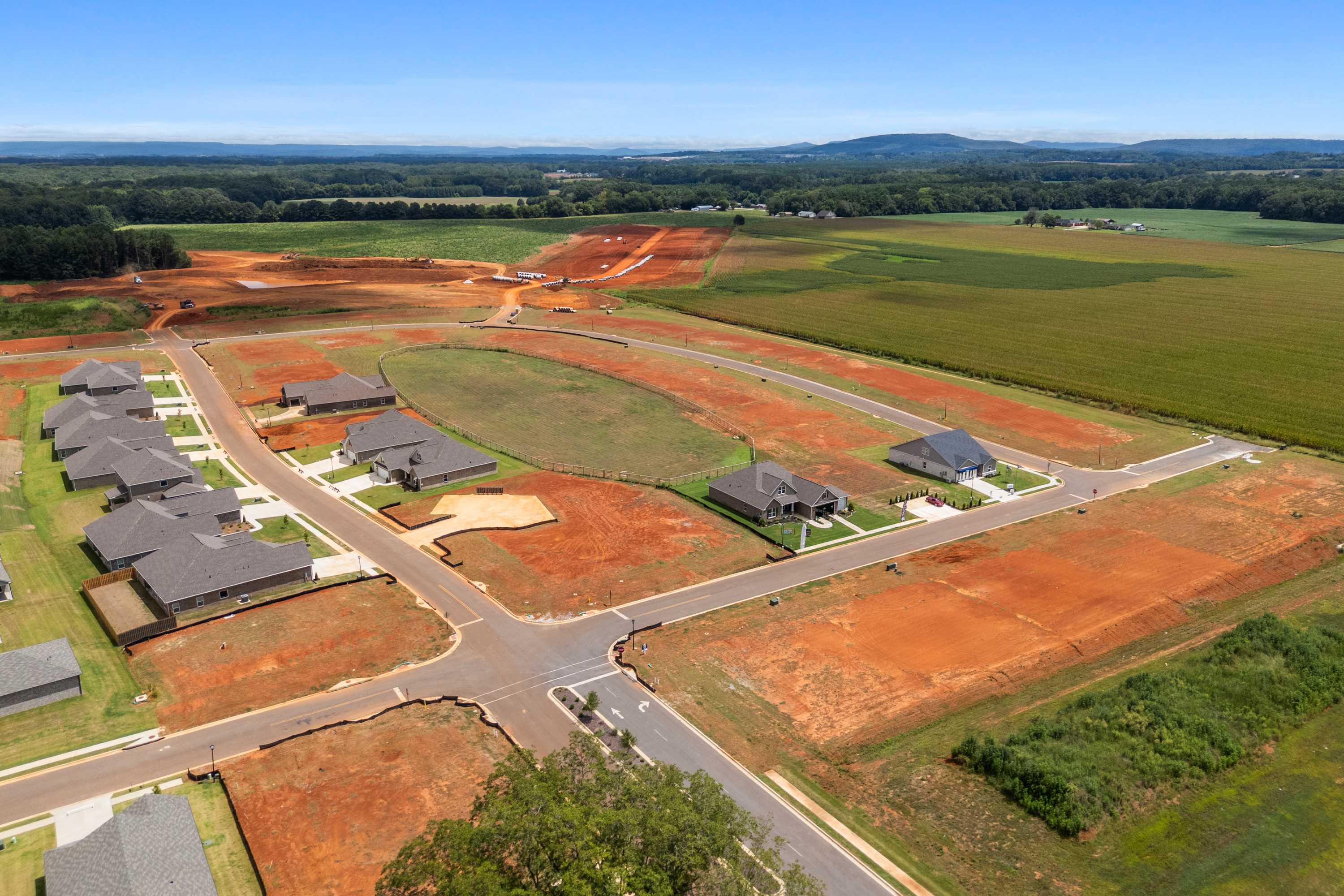 Aerial view of new homes and construction sites at Kendall Farms in Toney Alabama with red clay lots surrounding fields