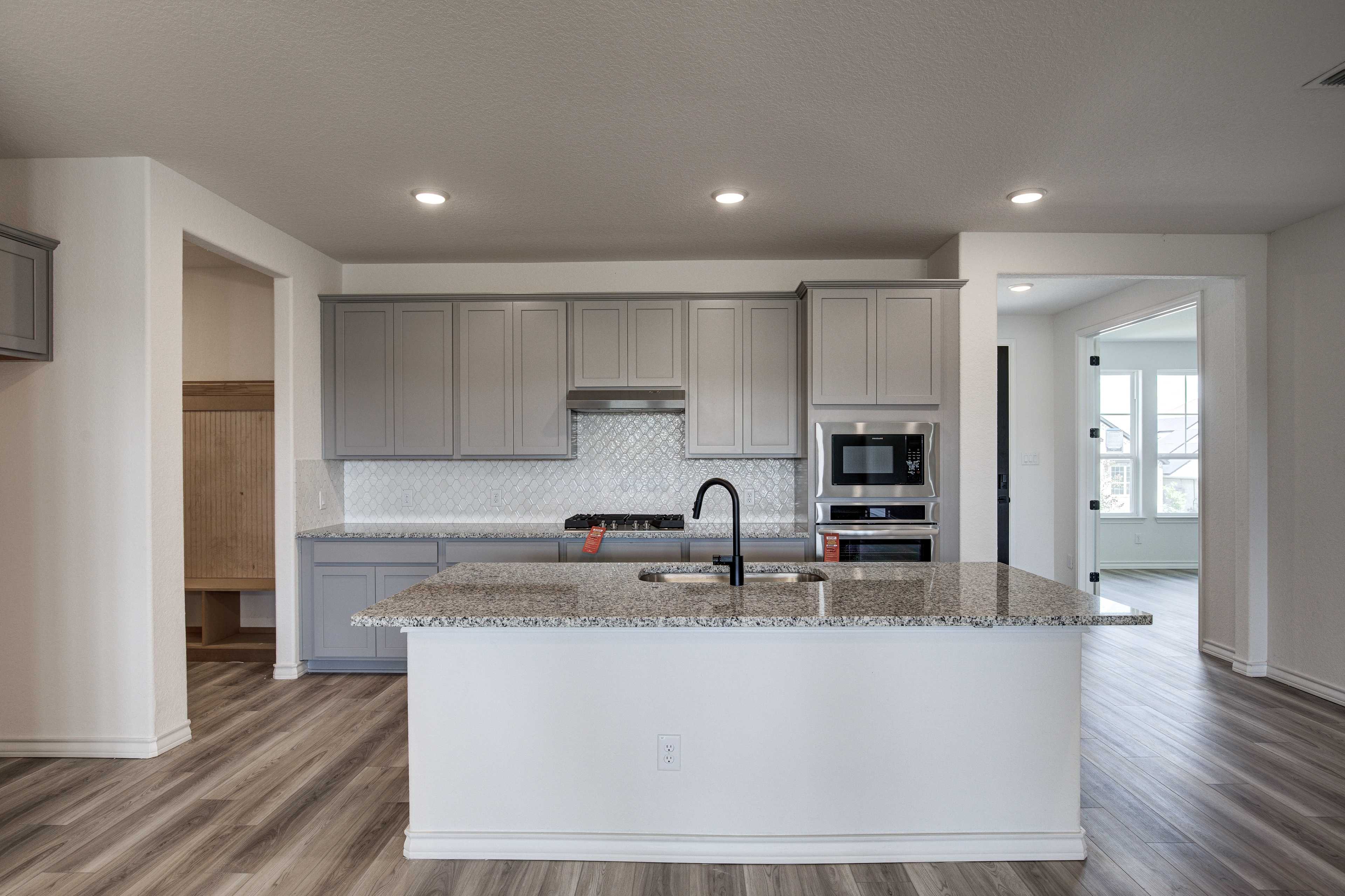 Spacious modern kitchen in The Lanier featuring gray shaker cabinets, white quartz island, stainless steel appliances, and open layout