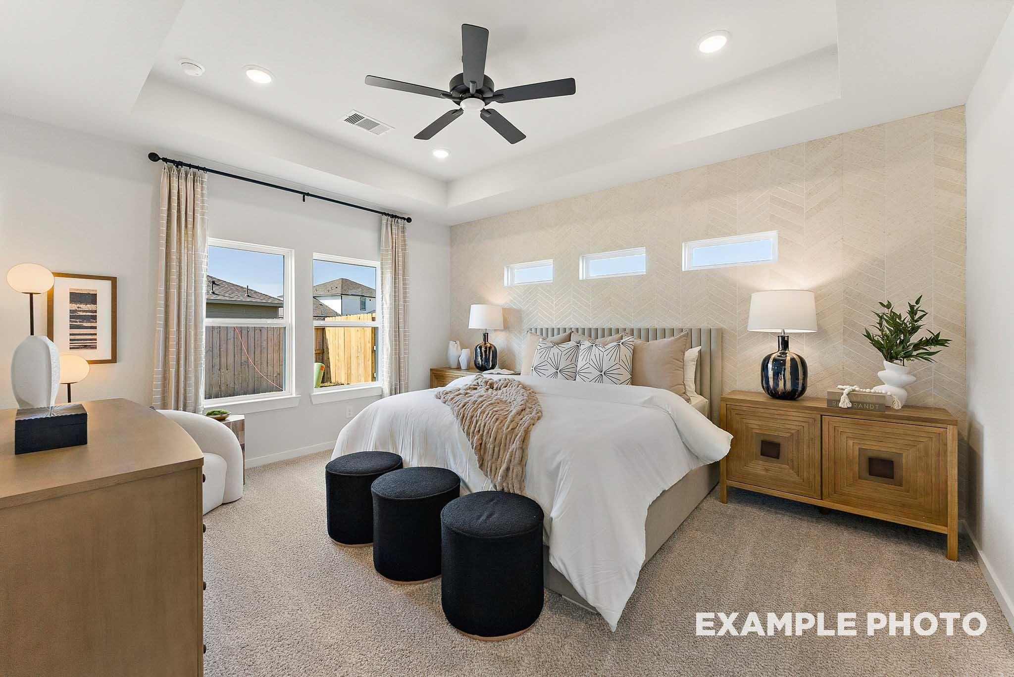 Modern primary bedroom with tray ceiling and textured accent wall in The Everett E floor plan, Sundance Cove, Crosby, TX.