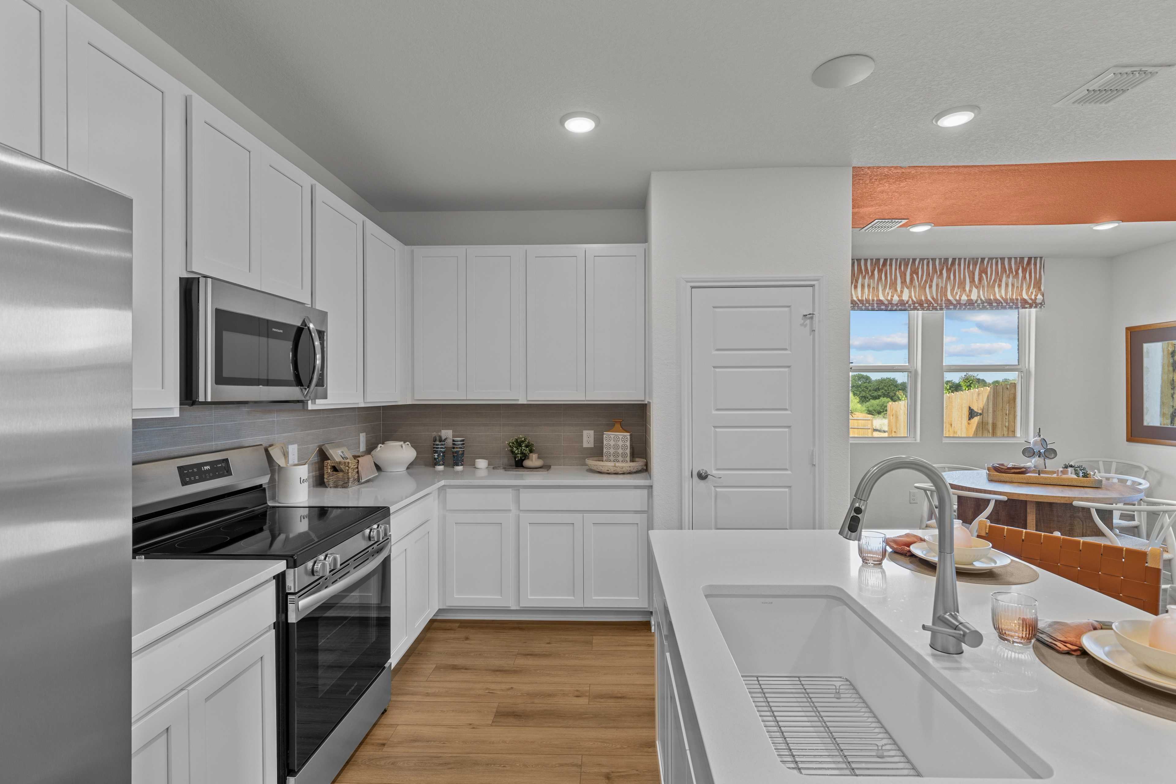 Spacious Daphne H kitchen with white cabinets, stainless steel appliances, large island sink, and open dining area