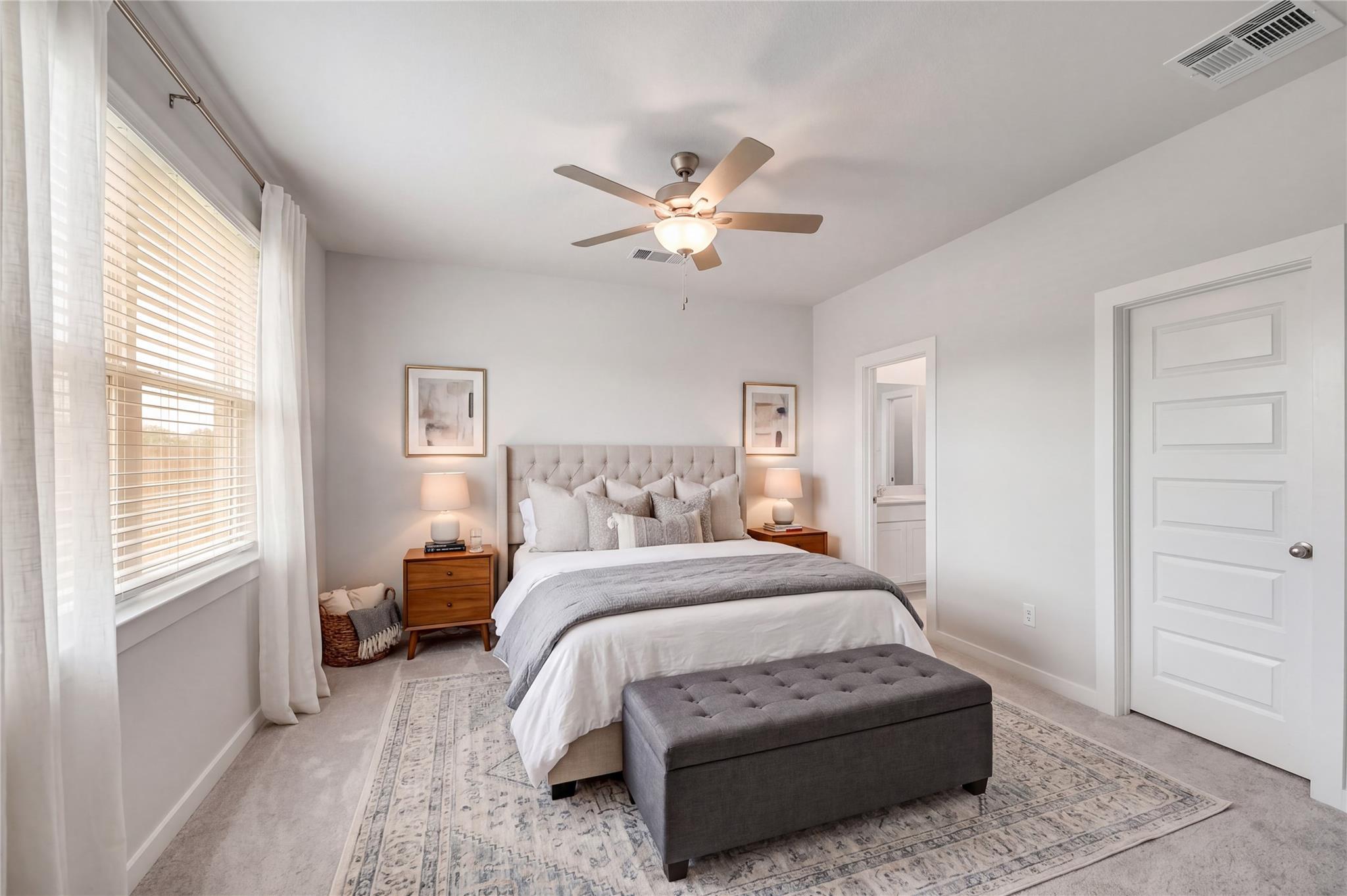 Bright primary bedroom with tufted headboard, ceiling fan, and natural light in Davidson Homes The Frio F, Cleveland, Texas.