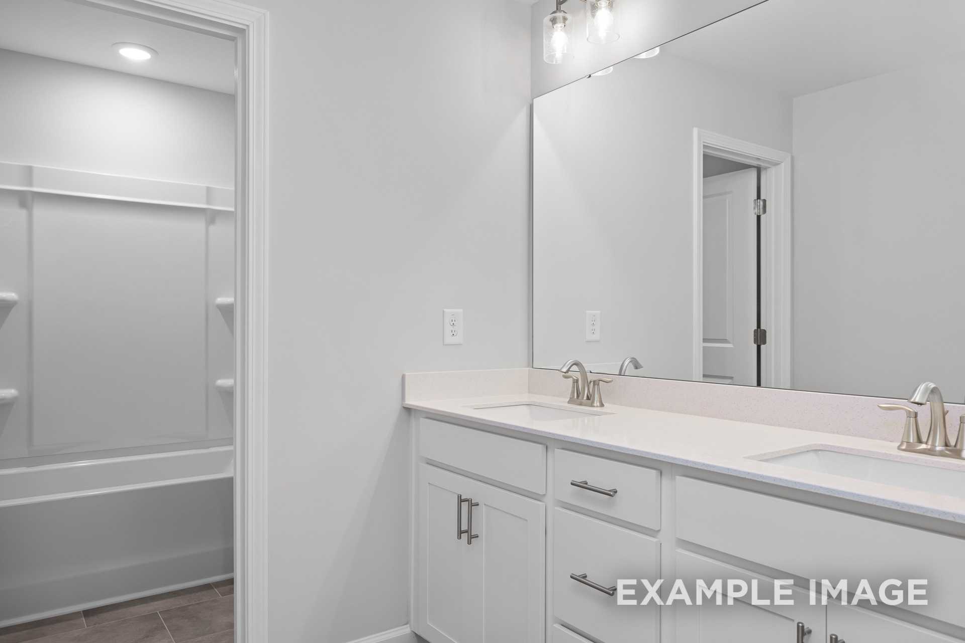 Spacious master bathroom in The Preston B featuring white double vanity, soaking tub, walk-in shower, and large mirror