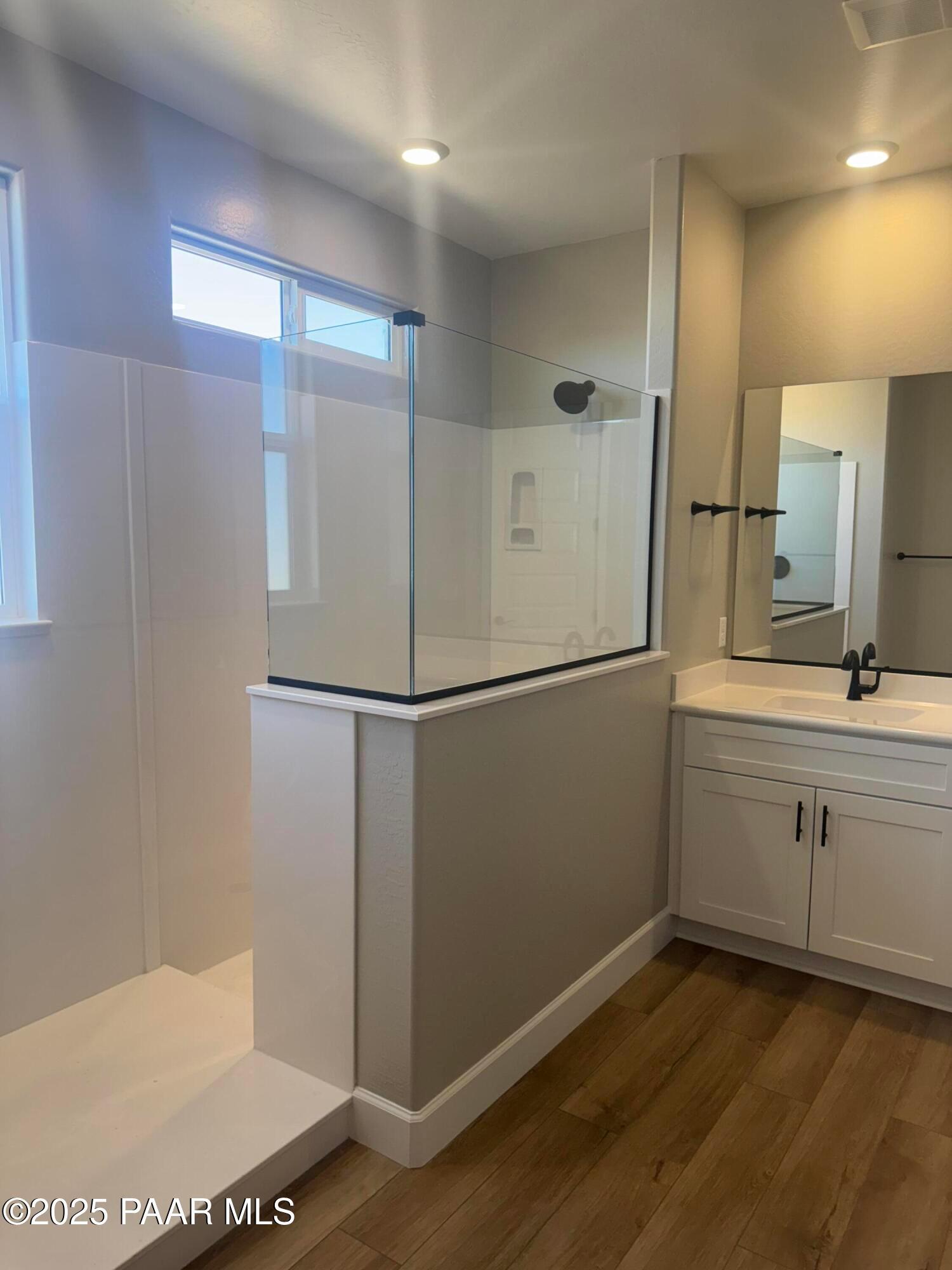 Modern master bathroom with frameless glass shower, single vanity sink, and wood flooring in Evermore Homes The Summit B, Prescott Valley, AZ