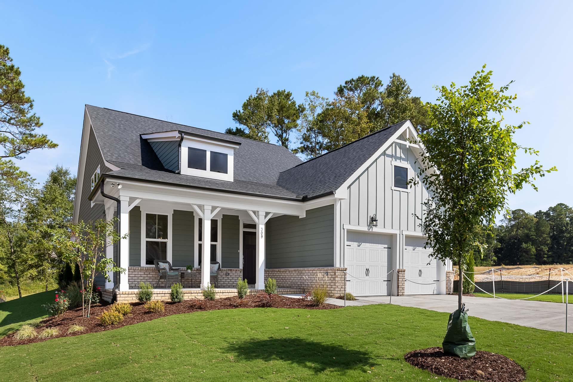 Modern farmhouse home exterior in Glenmere Knightdale NC with gray siding, covered porch, and landscaped yard by Davidson Homes