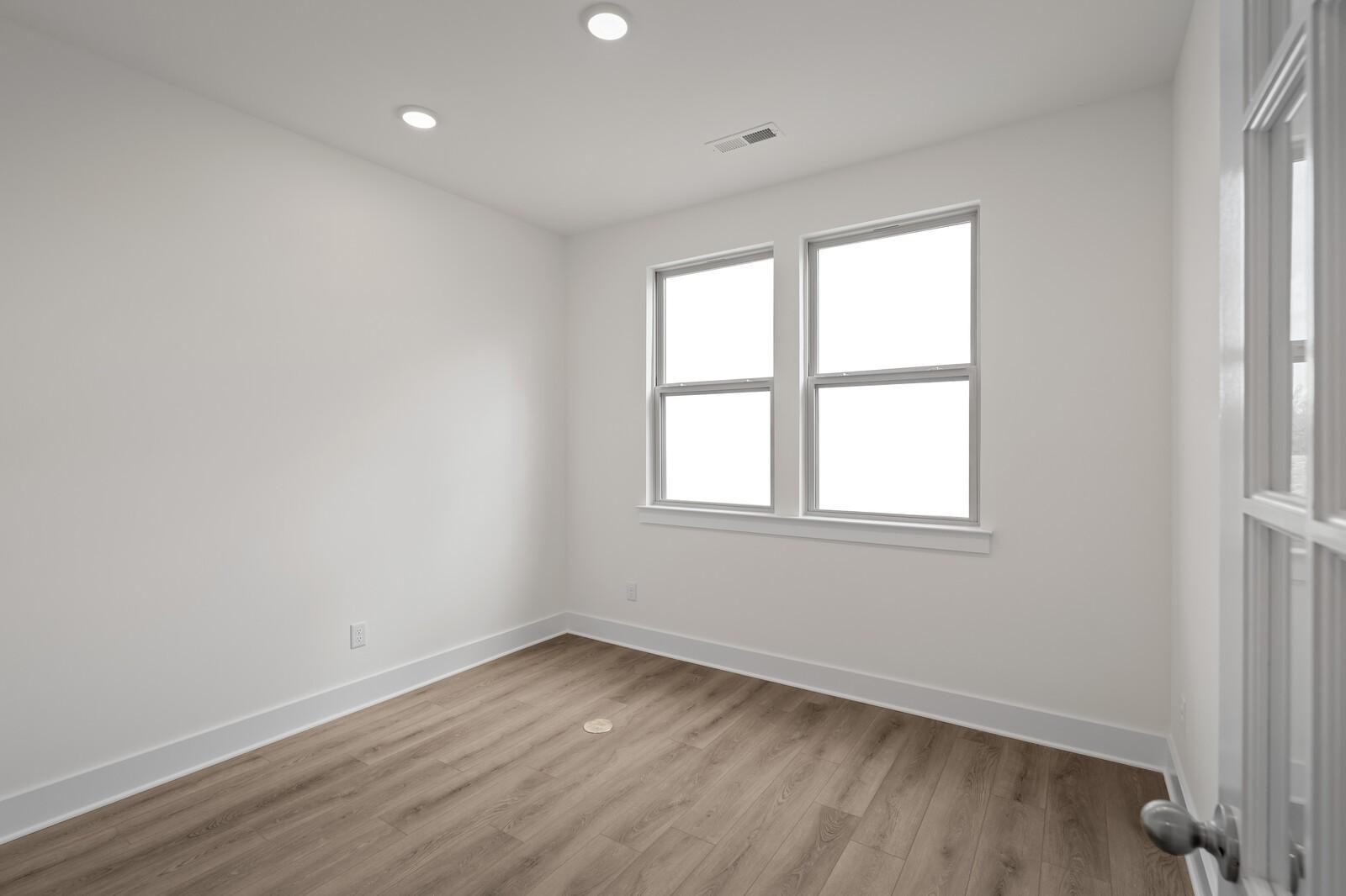 Bright secondary bedroom with large windows, white walls, hardwood floors in The Willow C, Davidson Homes, Gallatin TN
