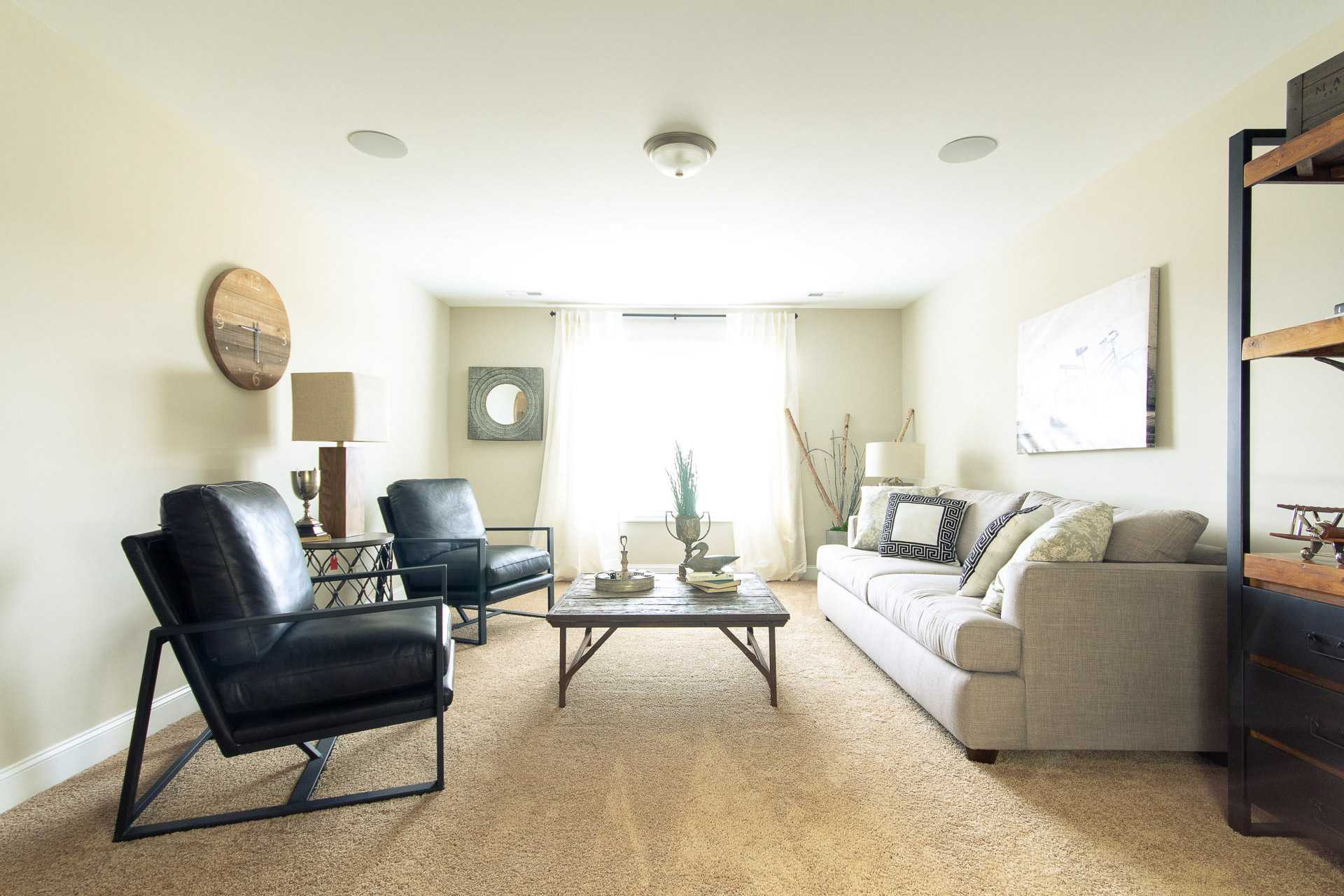 Cozy living room at Summer Pointe in Madison Alabama featuring leather armchairs, beige sofa, wooden coffee table, and neutral decor