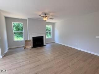 Spacious living room with fireplace and ceiling fan in The Daphne D floor plan at Woodland Crossing in Zebulon, NC.