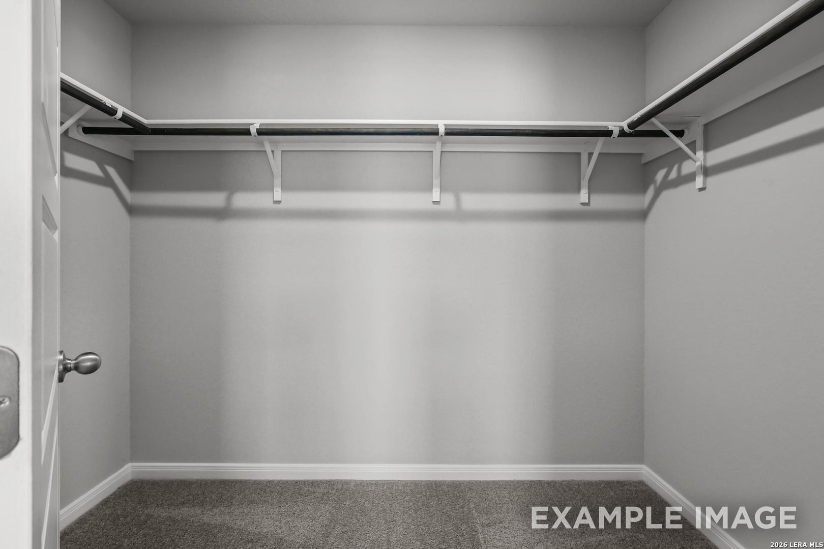 Walk-in closet with built-in shelving and carpet in The Gillian A floor plan by Davidson Homes in Cedar Heights, TX.