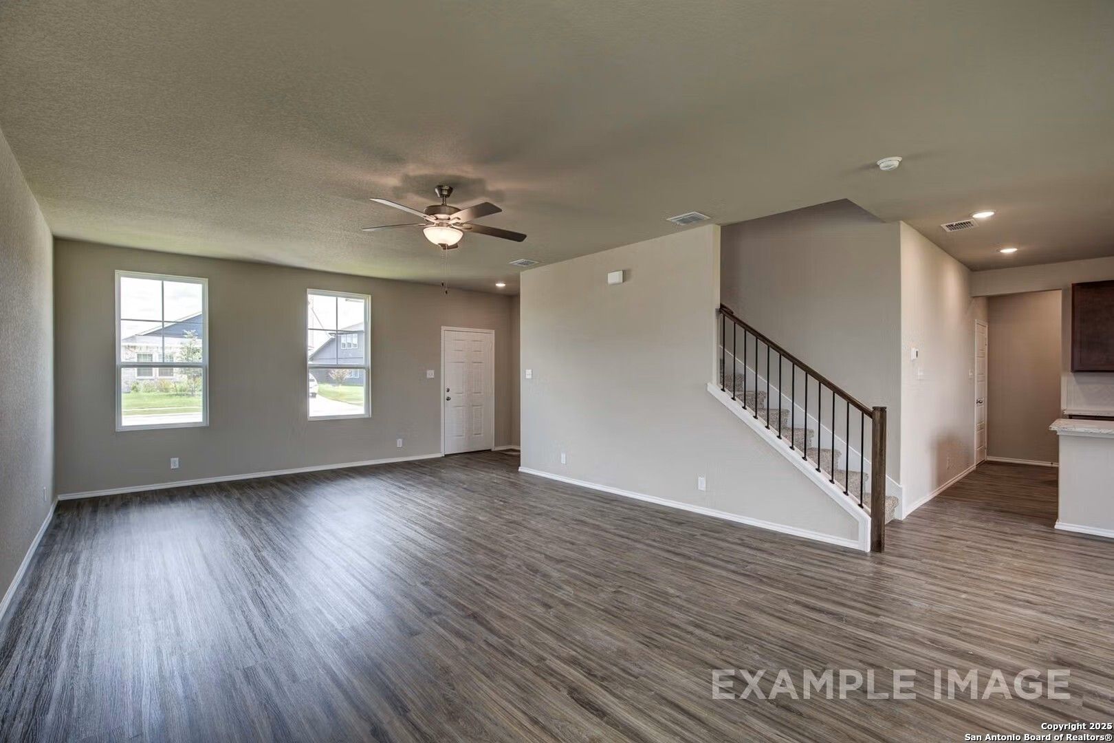 Spacious entryway with hardwood floors, wooden staircase, and large windows in Davidson Homes The Murray K, Comanche Ridge, San Antonio