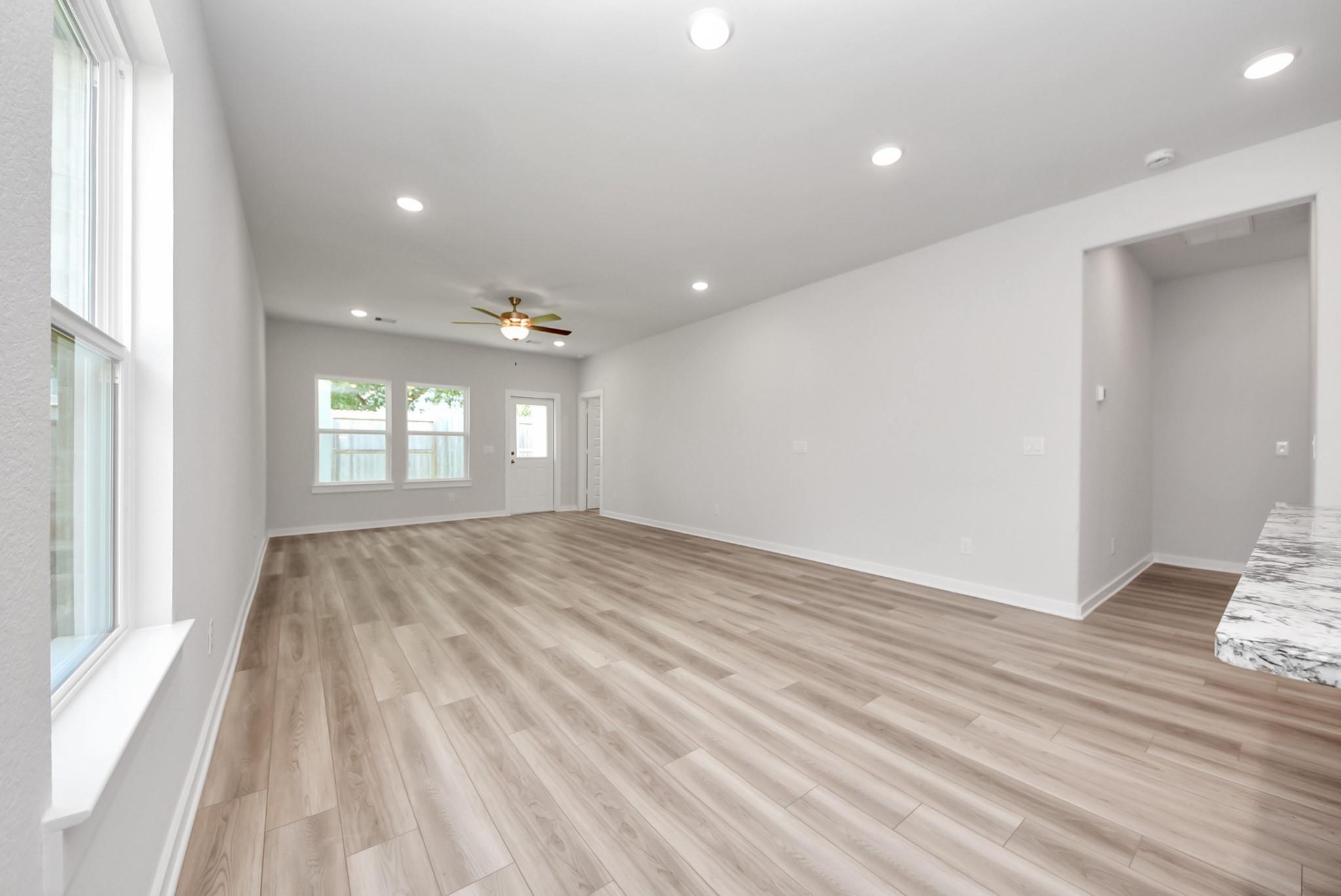 Spacious open-concept living area with wood-look flooring in The Sabine E floor plan at Windmill Estates, Magnolia, Texas.