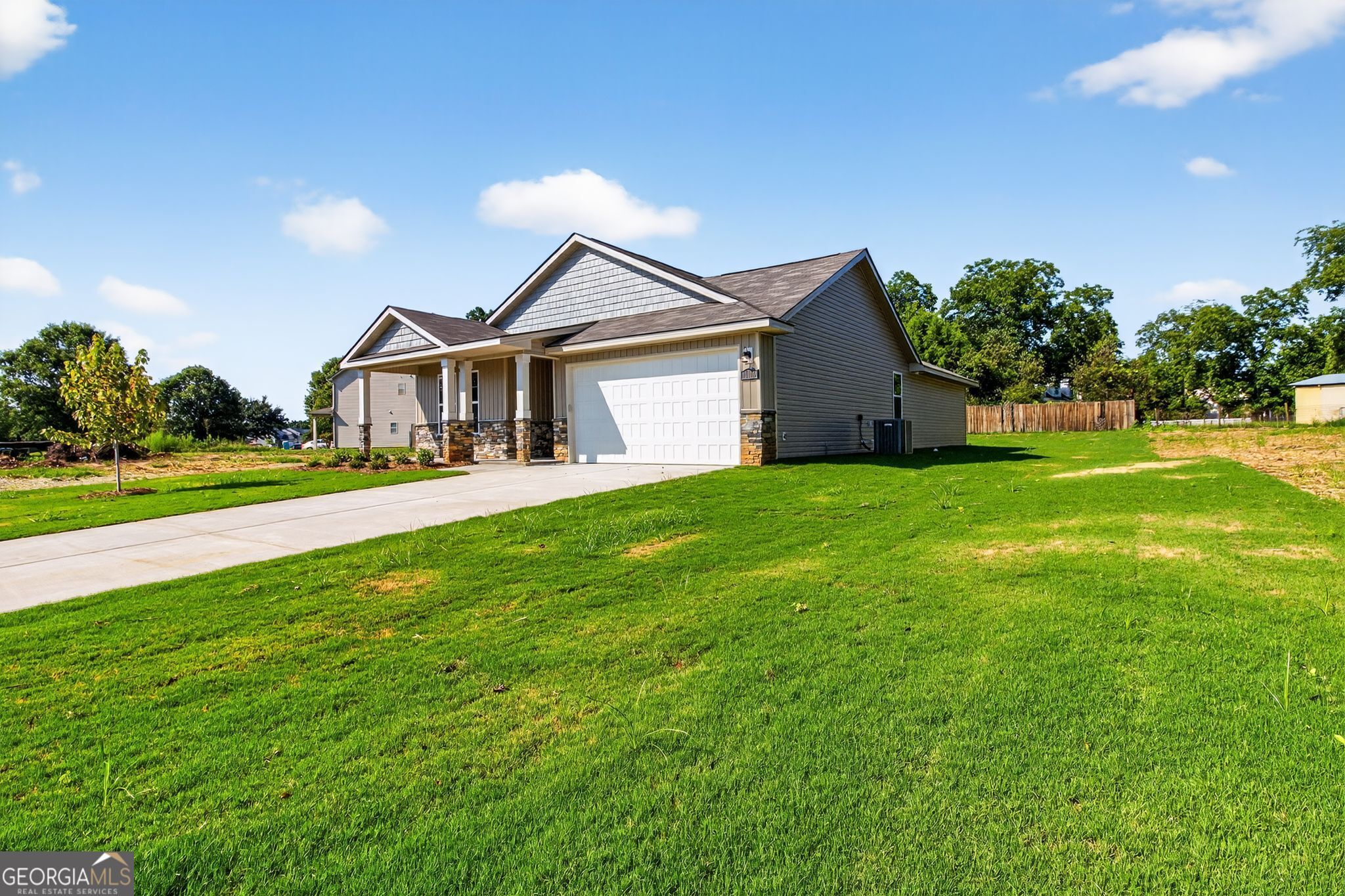 Modern 1-story 4-bedroom home with 2-car garage, front porch, driveway, and green lawn in Ivy Glen, Perry, Georgia