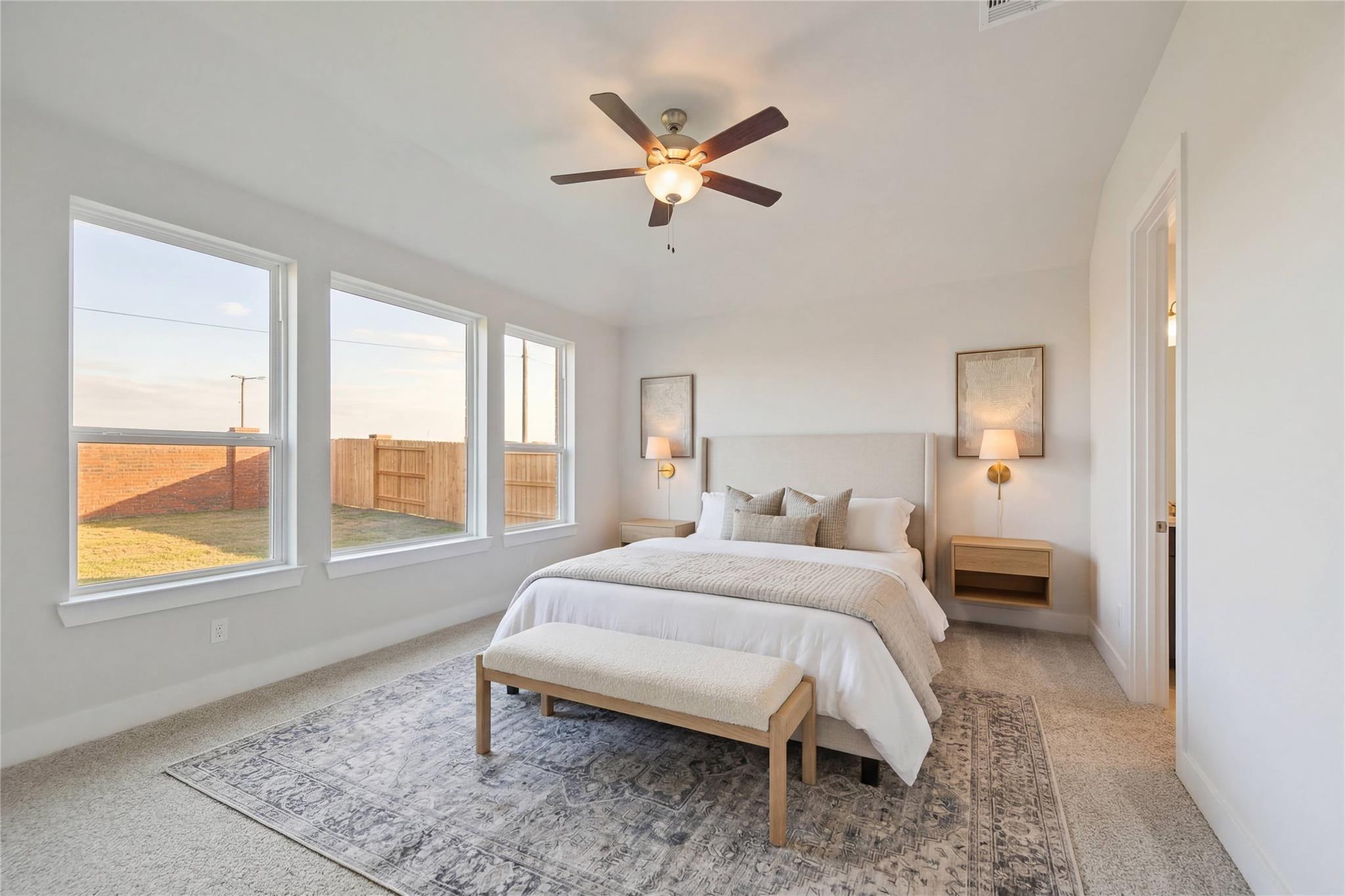 Bright master bedroom with king bed, ceiling fan, large windows overlooking backyard in Davidson Homes The Philip A, Texas City, Texas