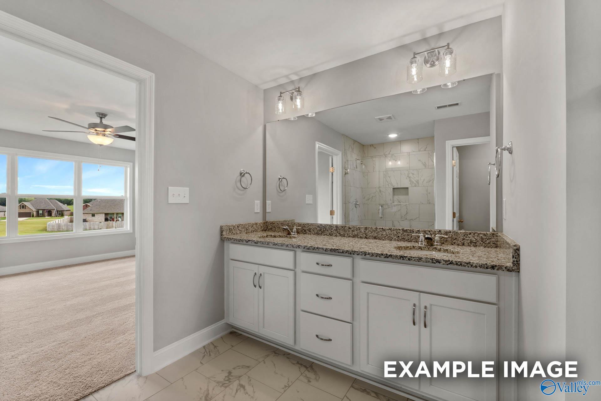 Elegant master bathroom featuring double granite vanity, sconce lights, and bedroom view in Davidson Homes Shelby B, New Market, AL
