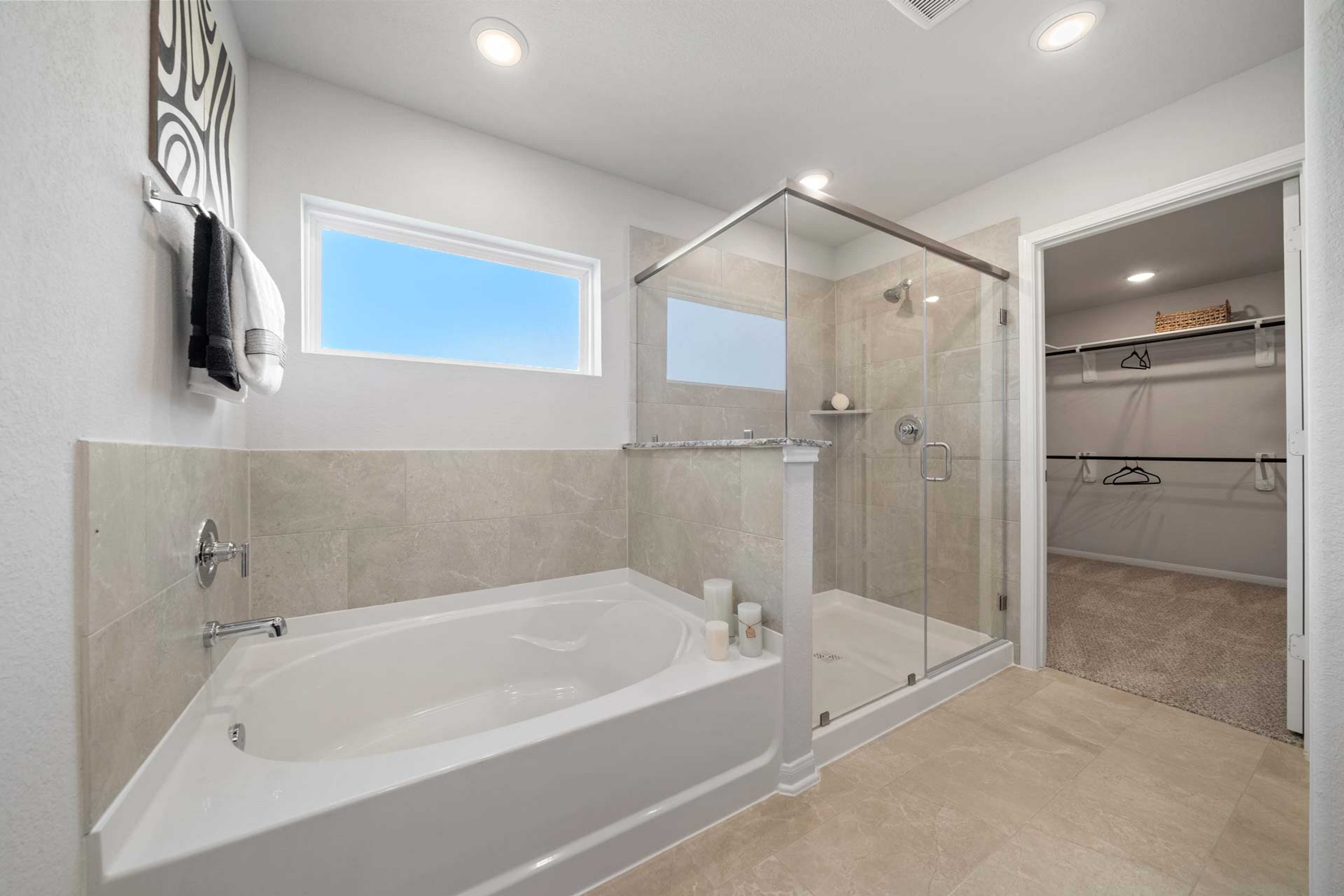 Elegant master bathroom at Windmill Estates in Magnolia Texas with freestanding soaking tub and glass shower