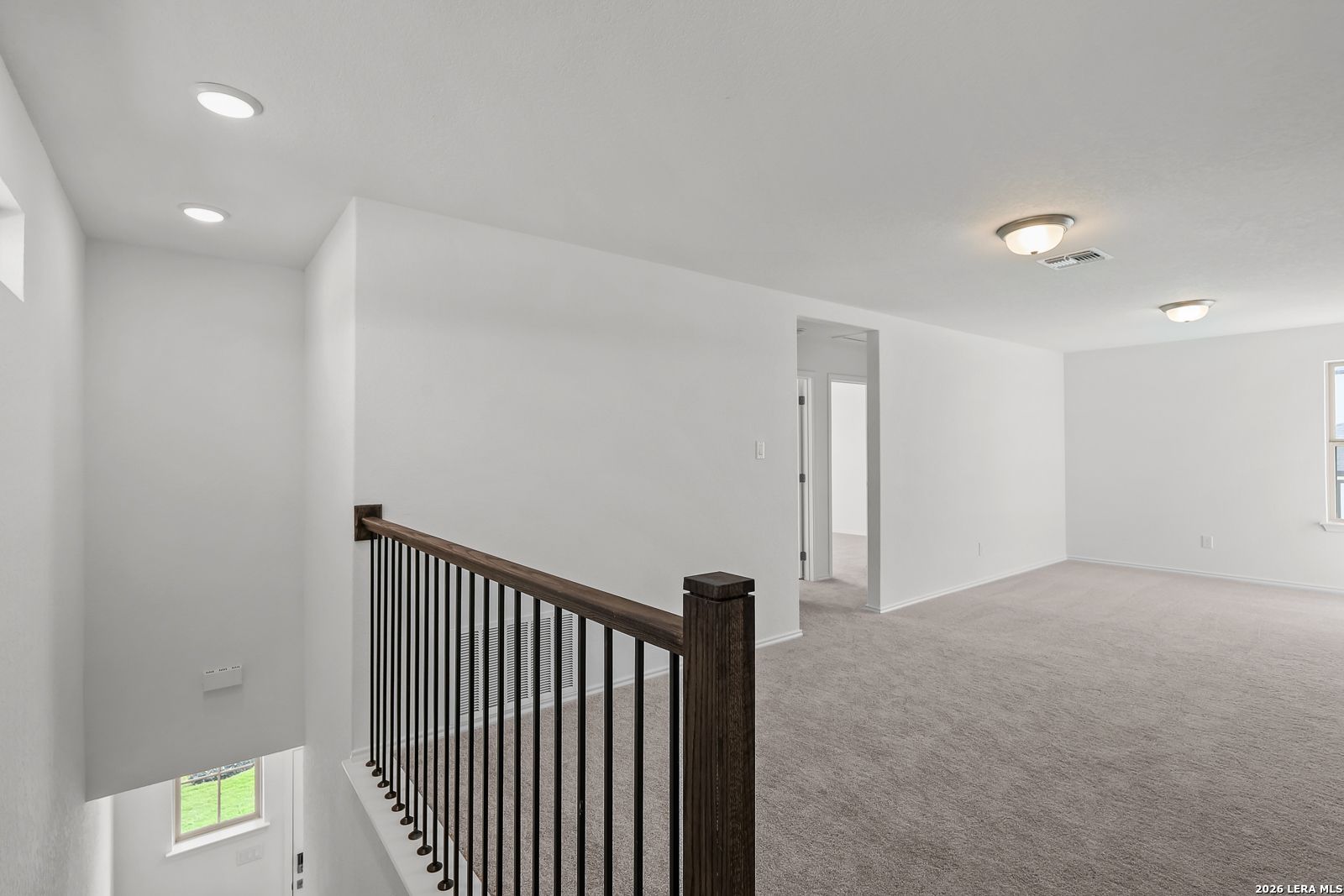 Spacious carpeted upstairs loft with iron railing in The Brazos B floor plan by Davidson Homes in Agave, San Antonio, Texas.