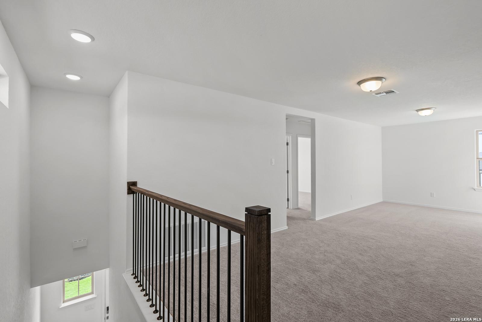 Spacious carpeted upstairs loft with iron railing in The Brazos B floor plan by Davidson Homes in Agave, San Antonio, Texas.