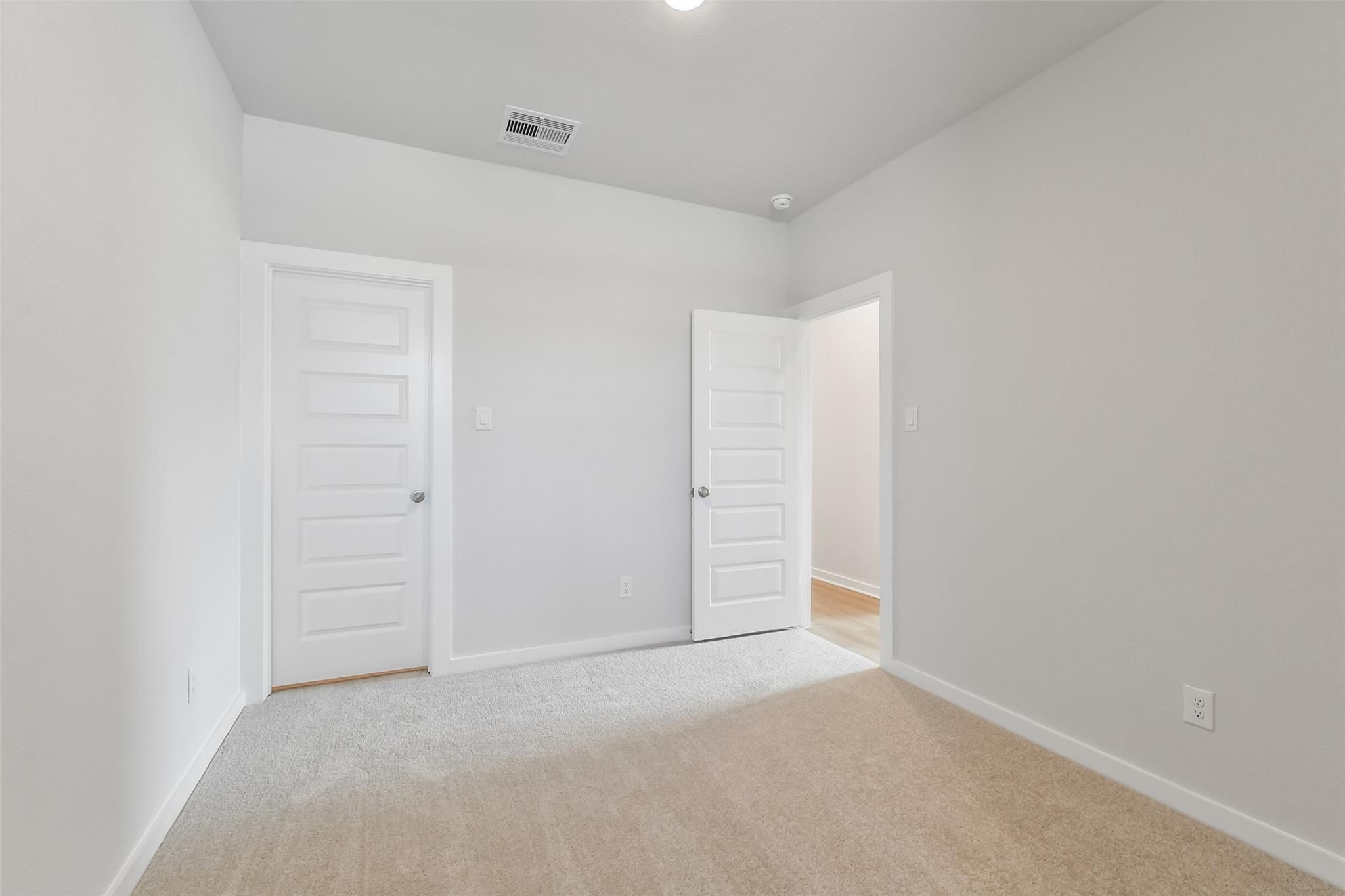Spacious secondary bedroom with white doors, beige carpet, and light gray walls in Davidson Homes The Colorado F, Cleveland, Texas