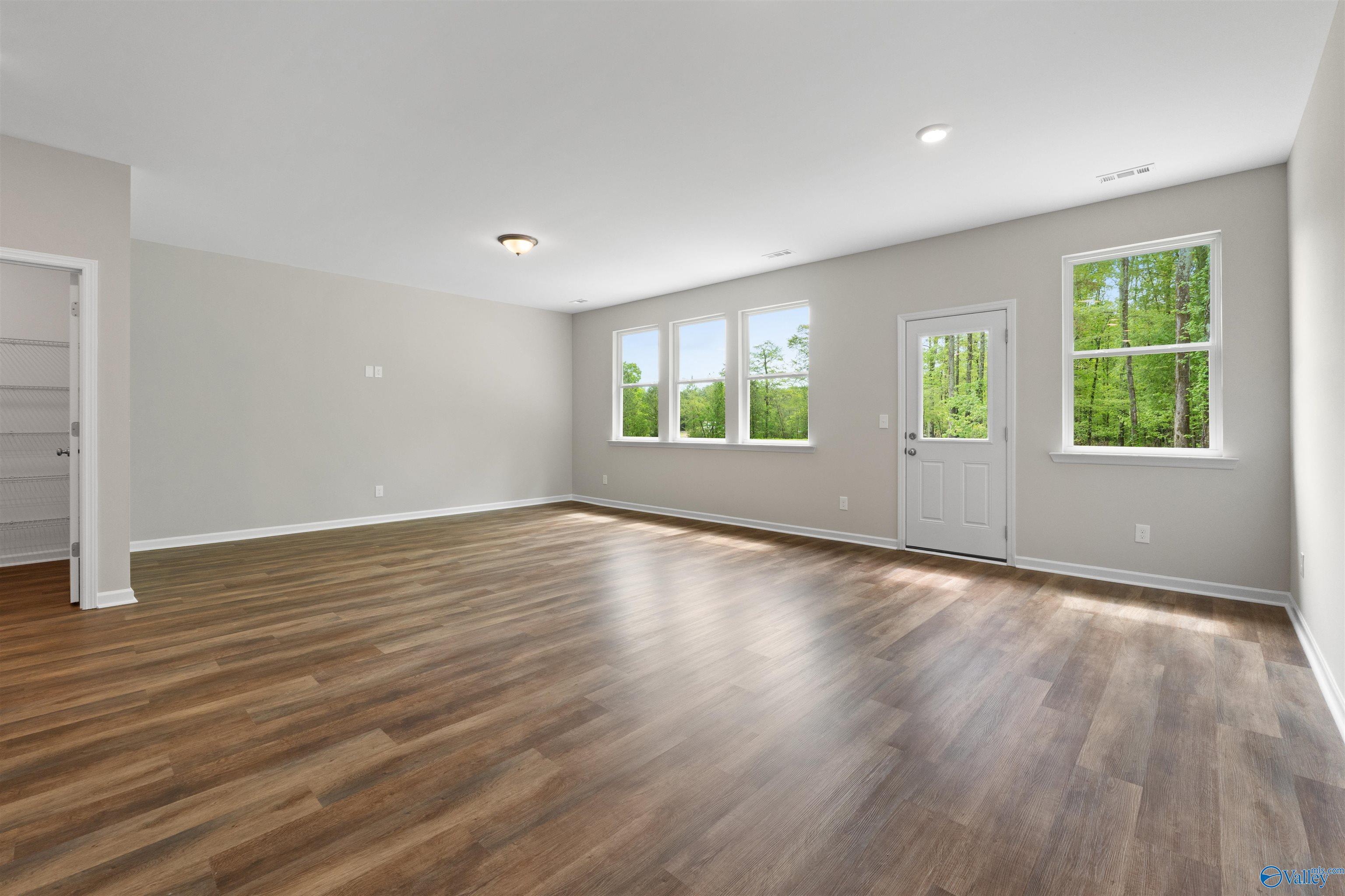 Spacious living room with hardwood floors, large windows, and patio door in Davidson Homes The Luna, Hazel Green, Alabama