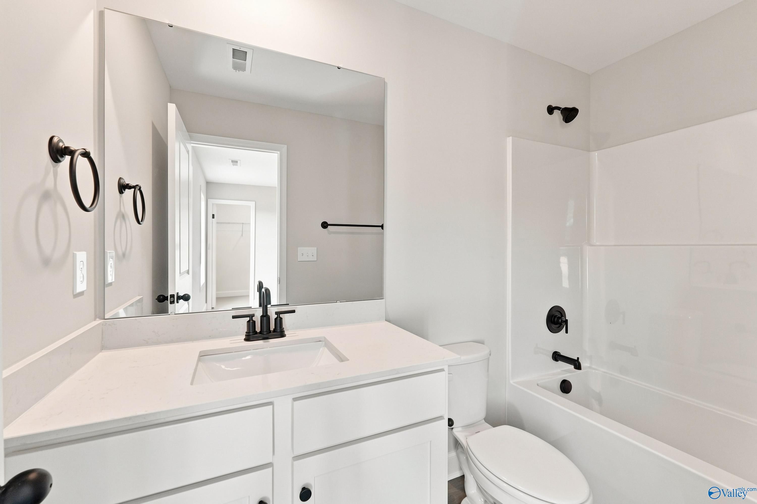 Bright white bathroom with quartz vanity, matte black fixtures, and tub-shower combo in Davidson Homes Chelsea B, New Market, AL