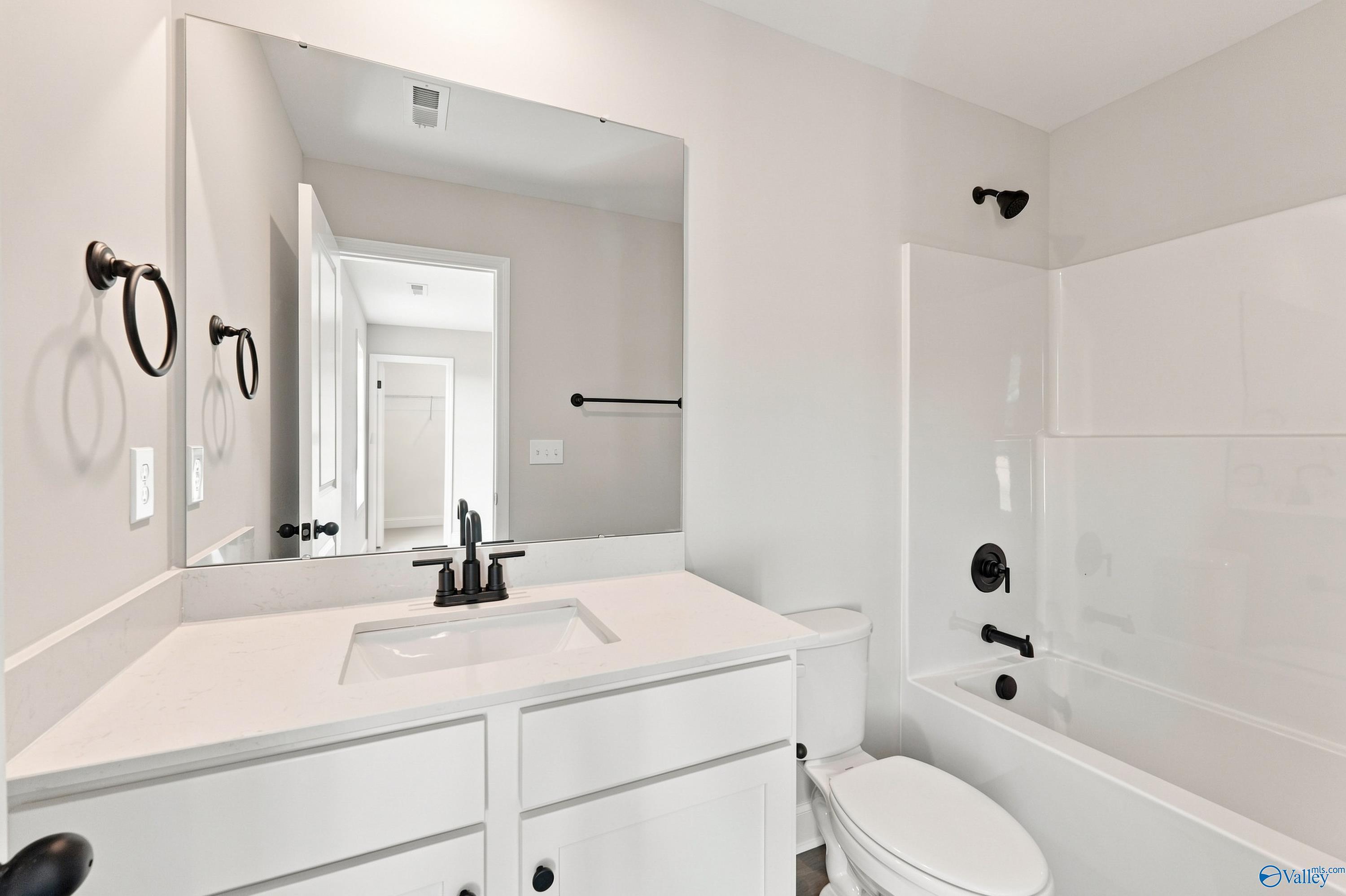 Bright white bathroom with quartz vanity, matte black fixtures, and tub-shower combo in Davidson Homes Chelsea B, New Market, AL