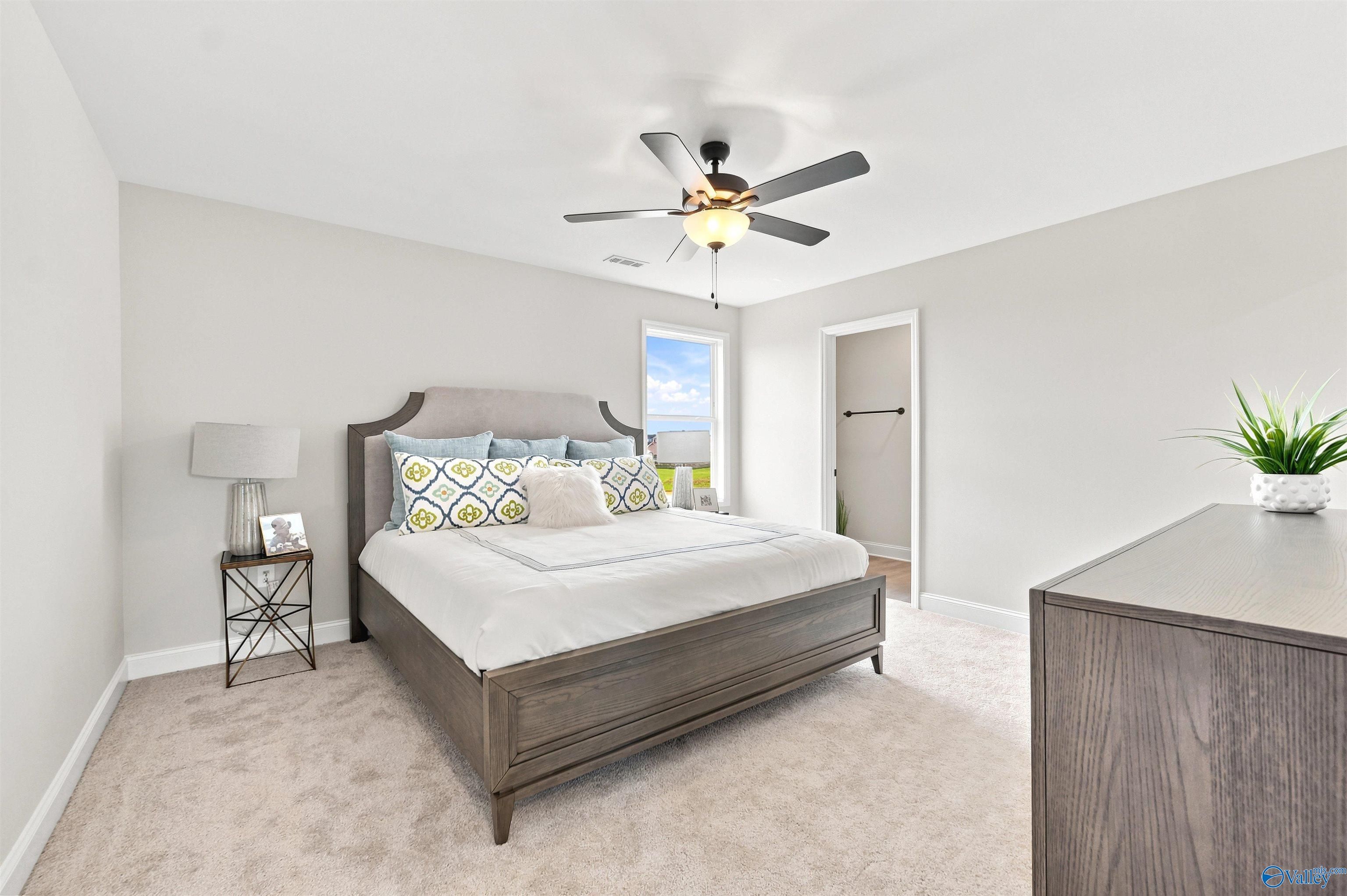 Bright primary bedroom with carpet and ceiling fan in The Burton B floor plan by Davidson Homes in New Market, AL.