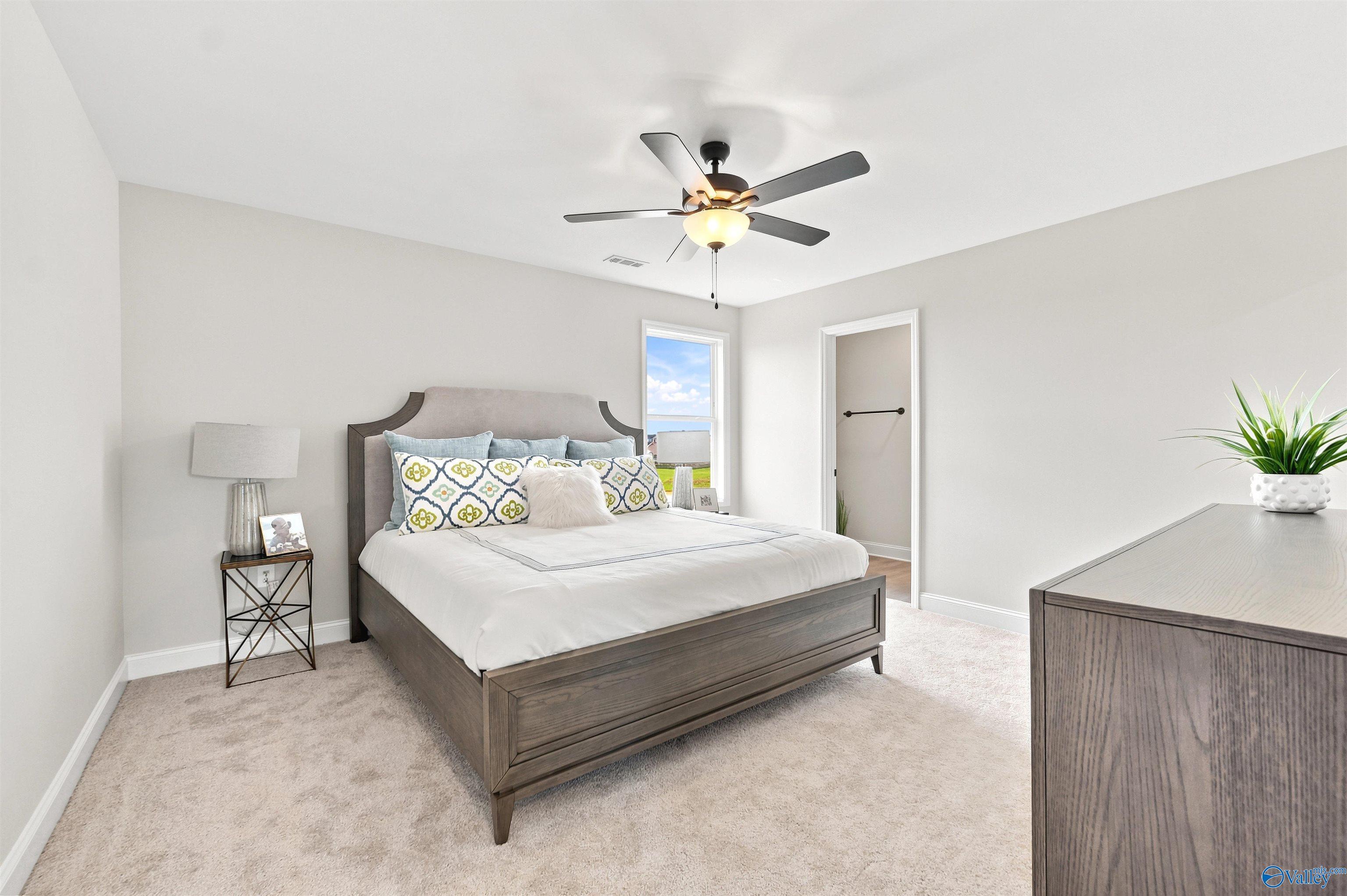 Bright primary bedroom with carpet and ceiling fan in The Burton B floor plan by Davidson Homes in New Market, AL.