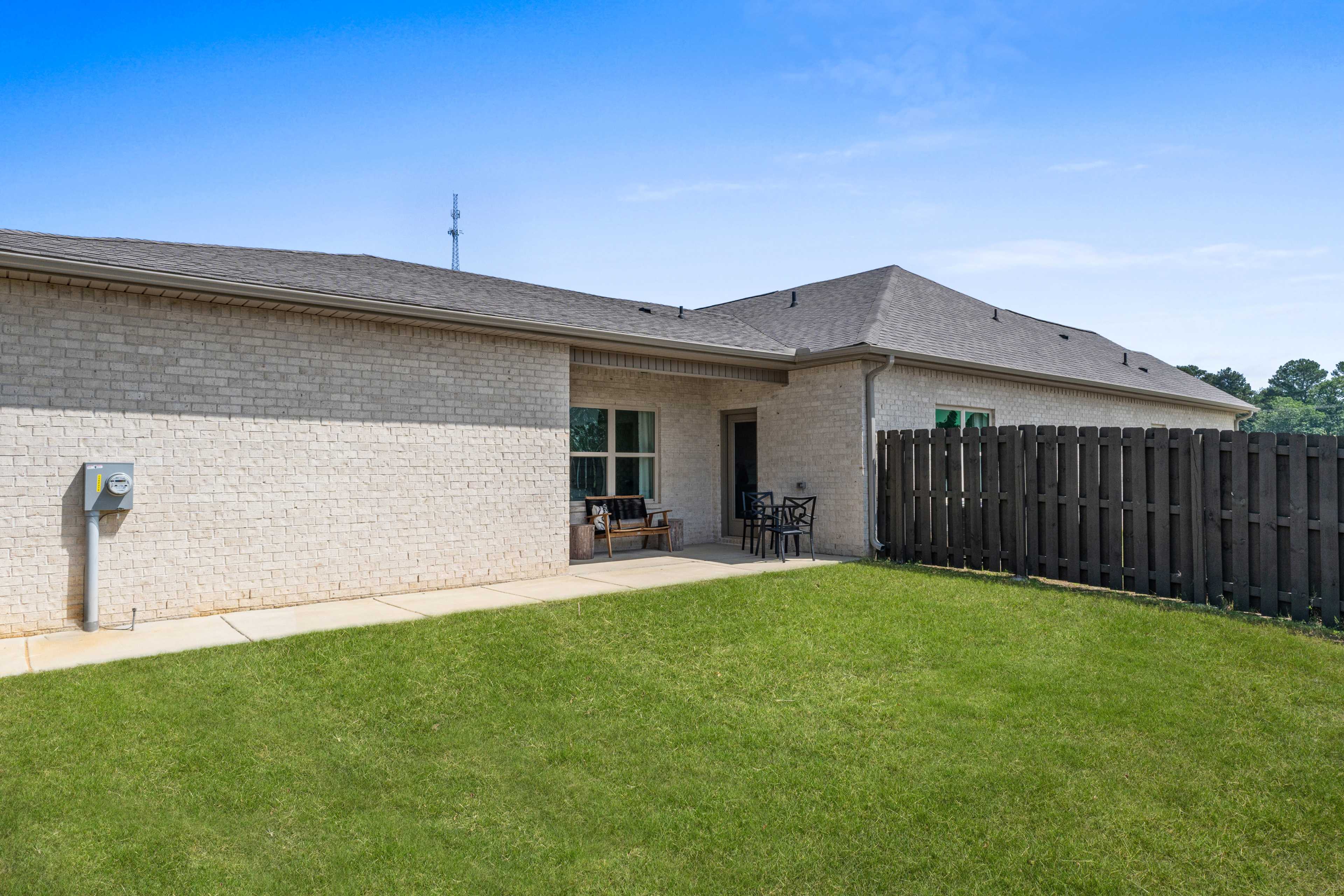 Brick home exterior at The Retreat at Cain Park in Hartselle Alabama with covered patio, glass doors, and fenced backyard lawn