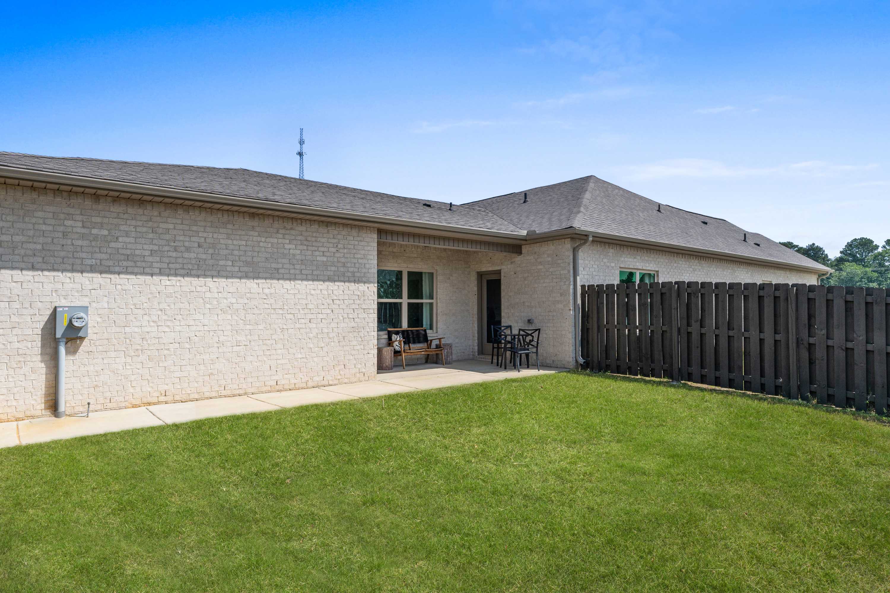 Brick home exterior at The Retreat at Cain Park in Hartselle Alabama with covered patio, glass doors, and fenced backyard lawn
