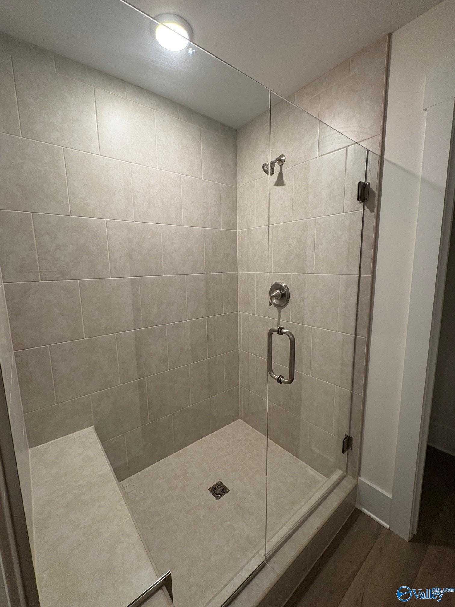 Modern walk-in shower with frameless glass door, subway tile walls, and built-in bench in Davidson Homes The Daphne C, Arab, Alabama