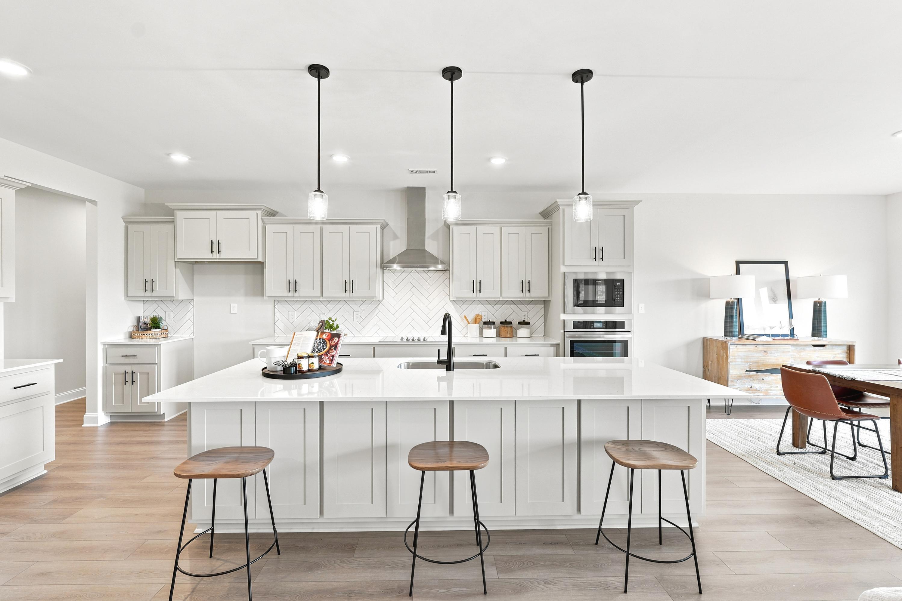 Modern kitchen with white island, pendant lighting, and herringbone backsplash at Riverton Preserve in Huntsville, Alabama.