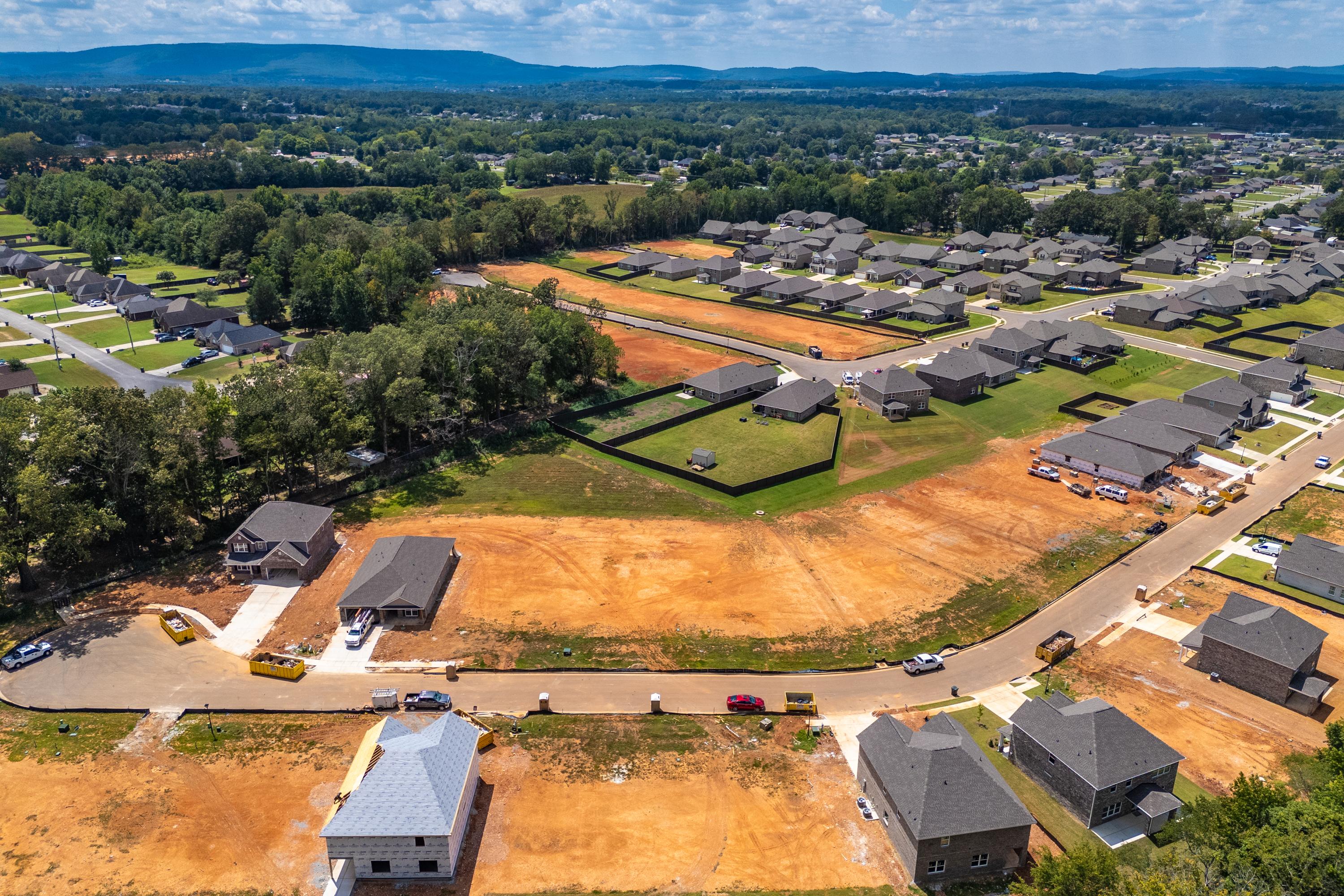Aerial view of Creek Grove neighborhood in New Market Alabama featuring new Davidson Homes construction sites wooded hills and dirt lots
