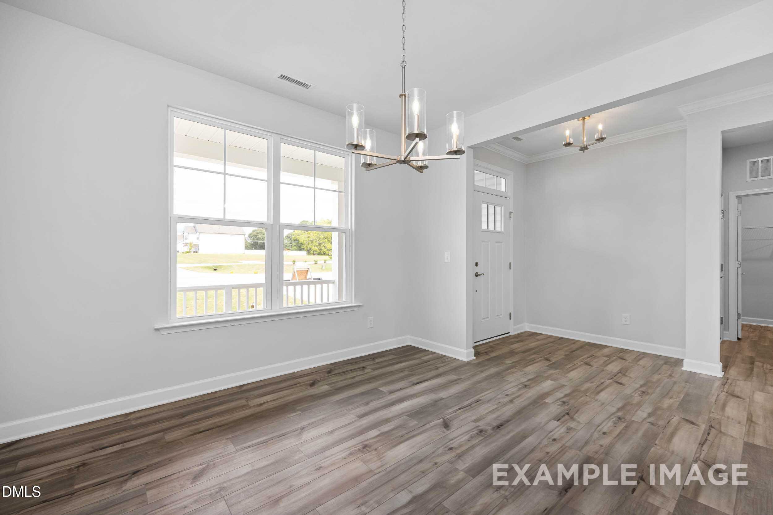 Bright entryway with chandelier, hardwood floors, and large window to covered porch in Davidson Homes The Ash B, Lillington NC