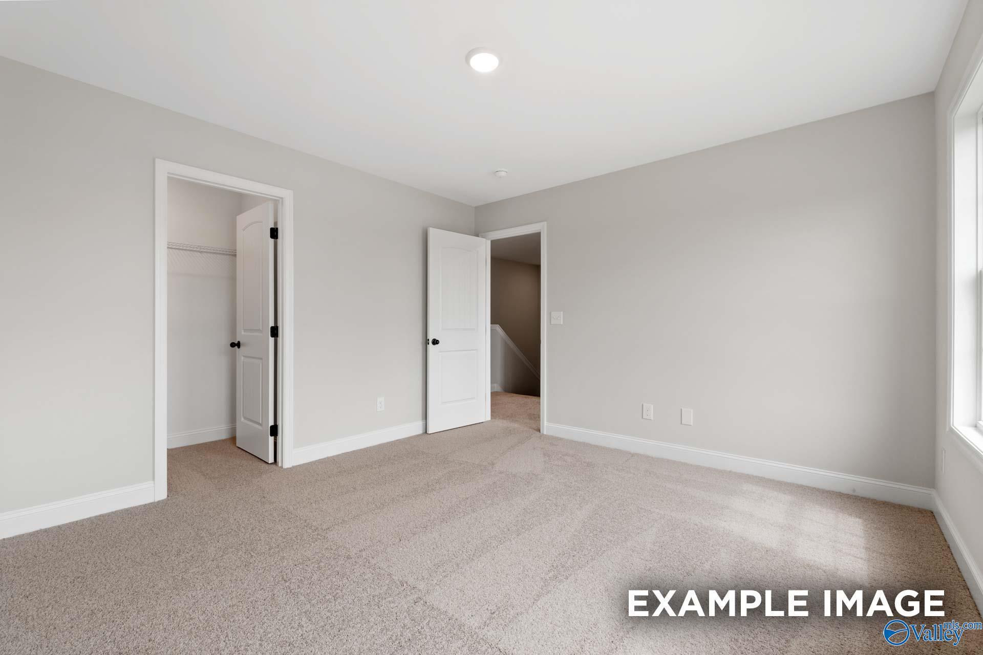 Spacious secondary bedroom with neutral carpet and walk-in closet in The Shelby B floor plan, Jaguar Hills, Huntsville.