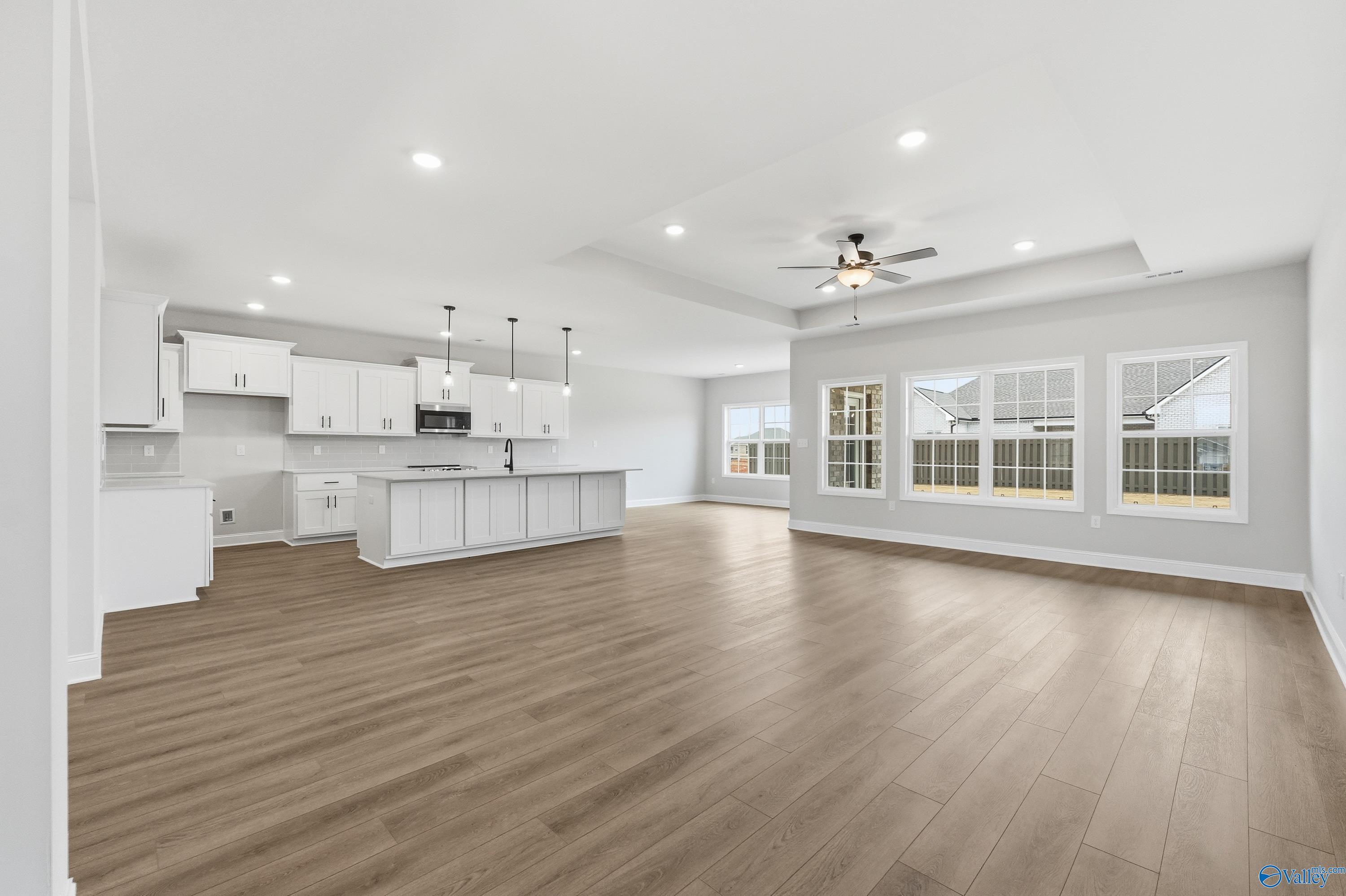 Open-concept kitchen and living area with white cabinetry, large island, and expansive windows in The Finleigh, Meridianville, AL
