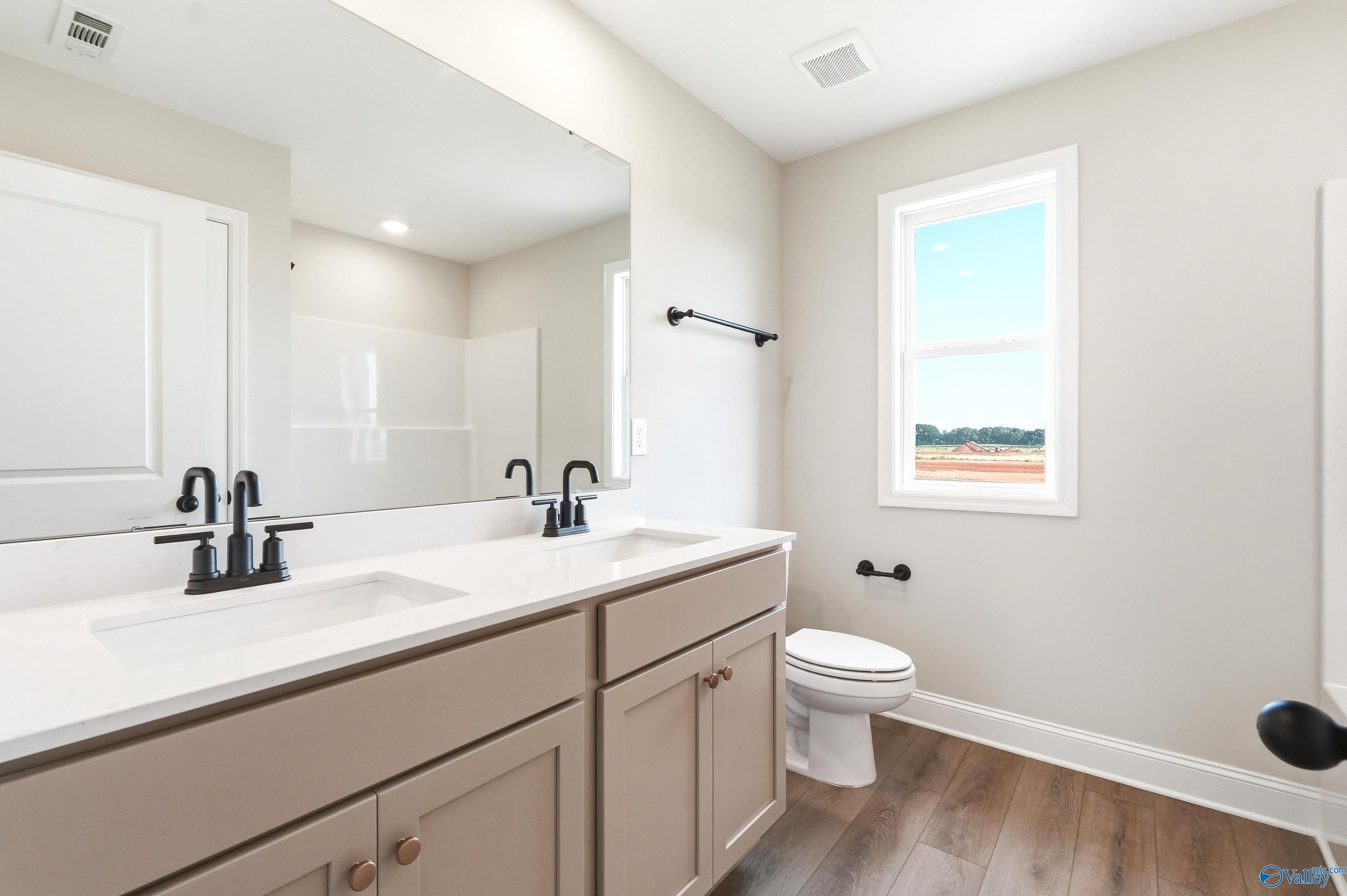 Modern bathroom with double vanity, quartz countertops, and matte black fixtures in The Shelby A home, Hazel Green, AL.