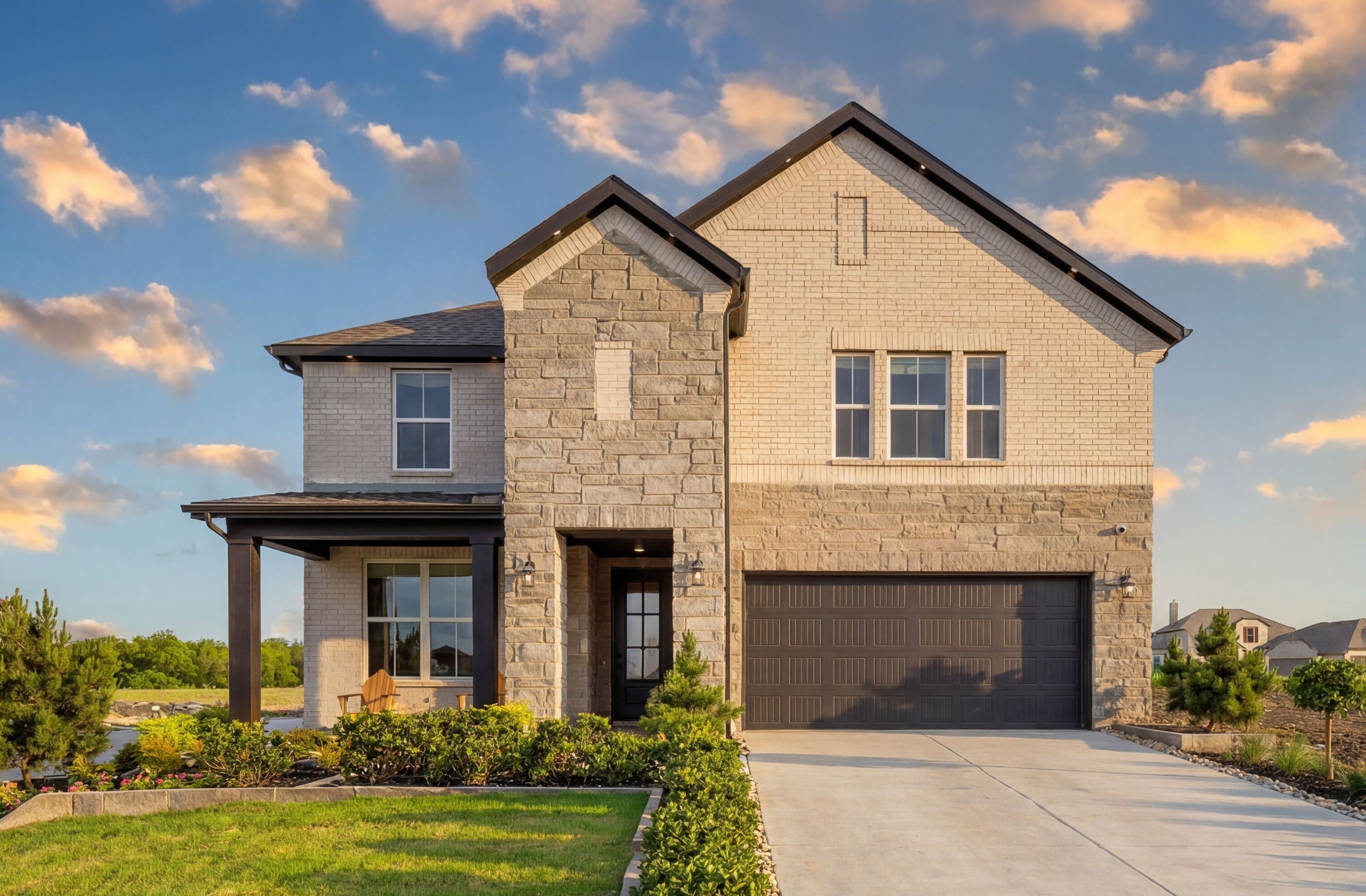 Modern stone and brick two-story home exterior at Mercer Meadows in Royse City, Texas with covered porch, garage and landscaped yard