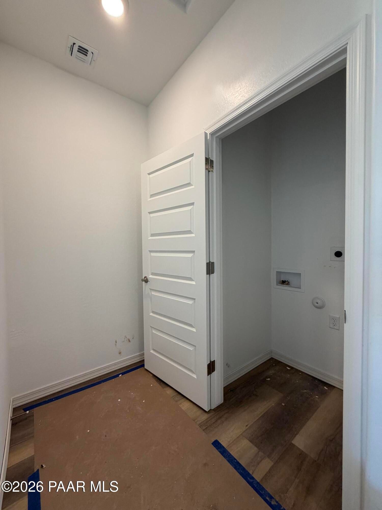 Laundry room with white paneled door, vinyl plank flooring, and washer hookups in Davidson Homes Marietta C, Prescott AZ