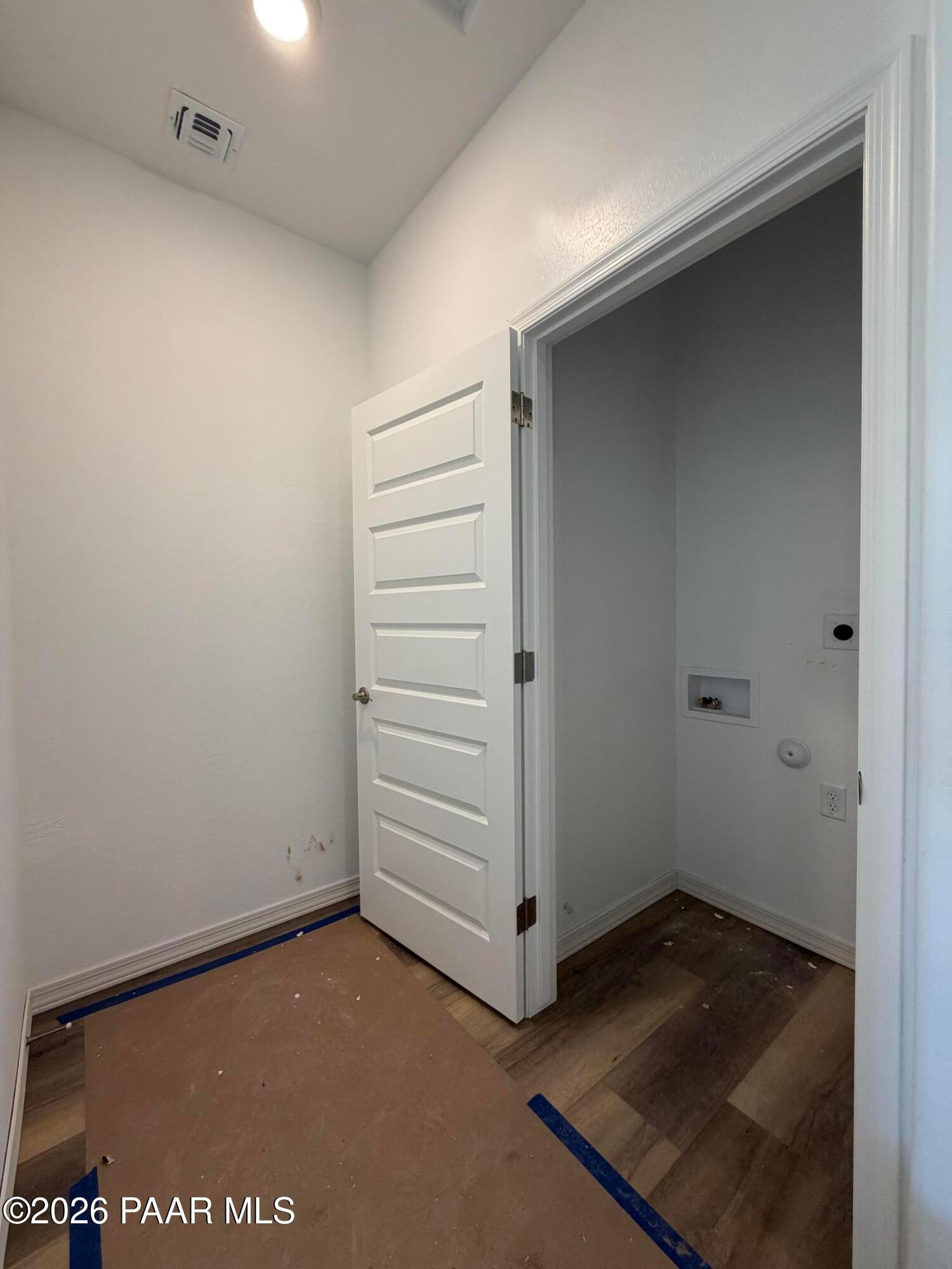 Laundry room with white paneled door, vinyl plank flooring, and washer hookups in Davidson Homes Marietta C, Prescott AZ