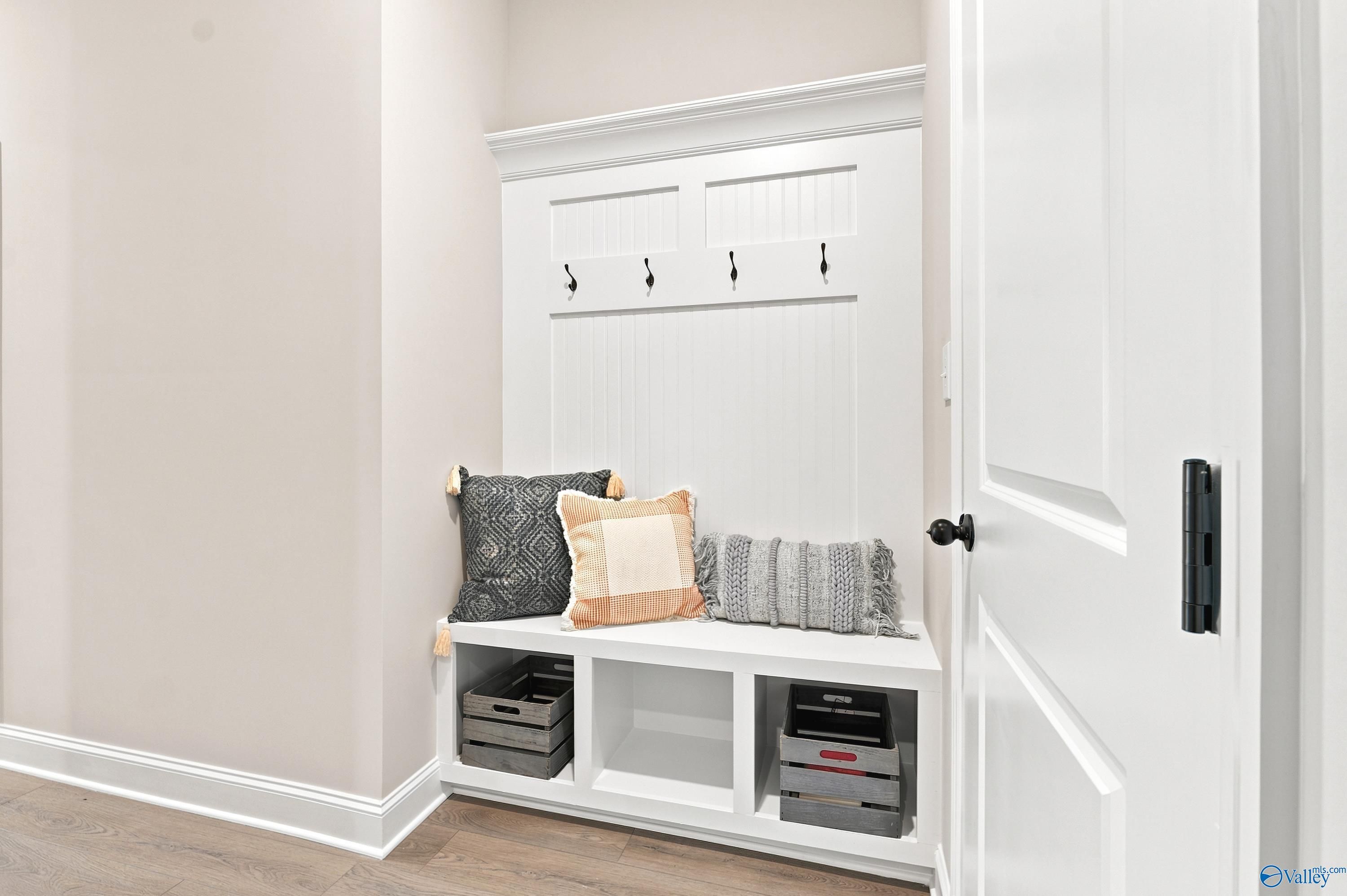White mudroom built-in bench with wall hooks and storage cubbies in The Finleigh floor plan, Riverton Preserve, Huntsville.