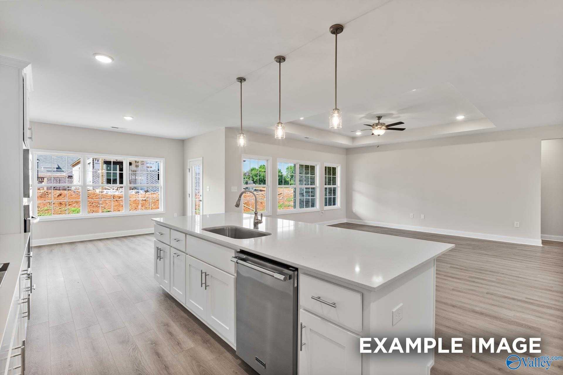Modern open-concept kitchen featuring white quartz island, stainless dishwasher, pendant lights, and large backyard windows in Davidson Homes The Finleigh, Meridianville, Alabama
