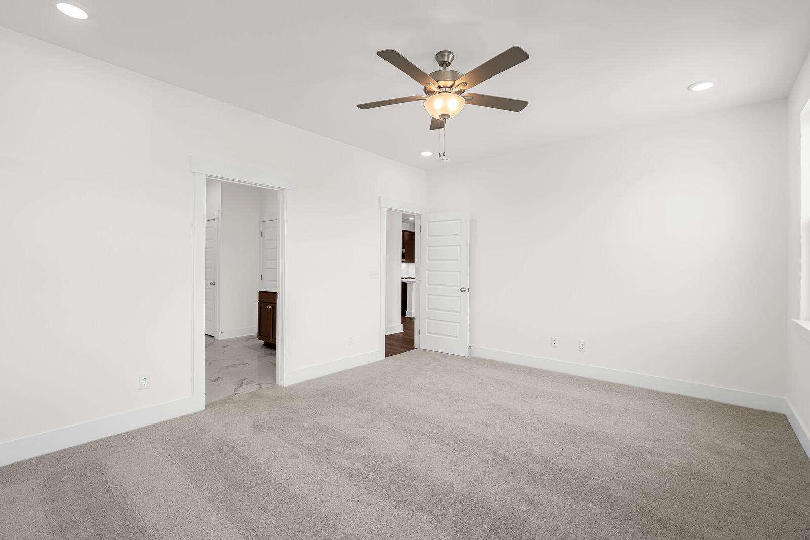 Spacious master suite with carpeted flooring and ceiling fan in The Cottonwood home design by Davidson Homes.