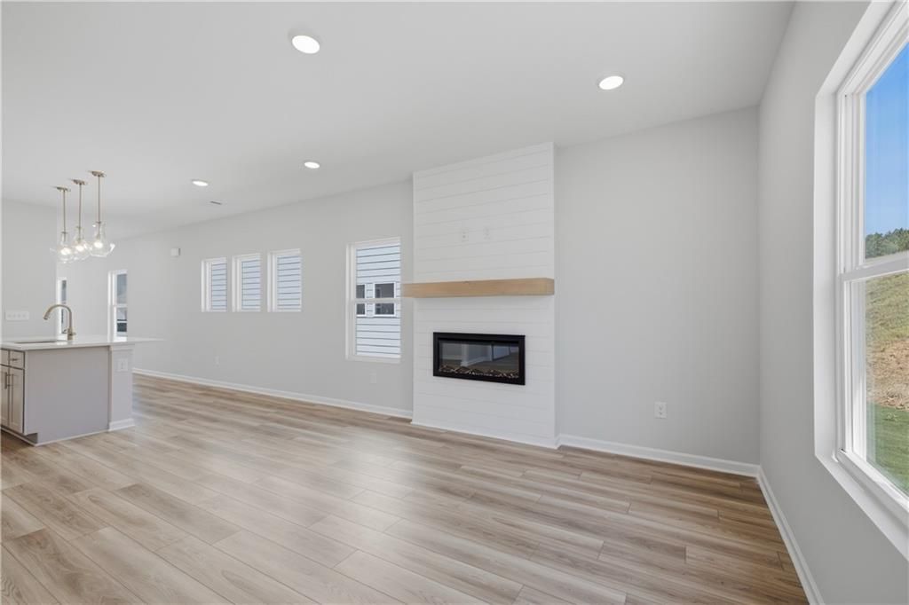 Bright open-concept living room with shiplap fireplace and hardwood floors in Davidson Homes Oconee B, The Bluffs, Canton, GA