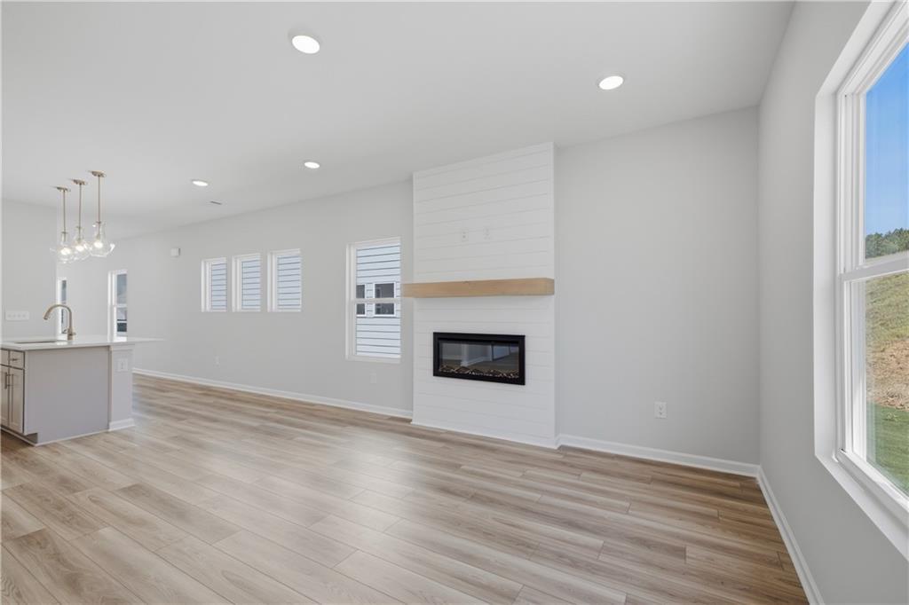 Bright open-concept living room with shiplap fireplace and hardwood floors in Davidson Homes Oconee B, The Bluffs, Canton, GA