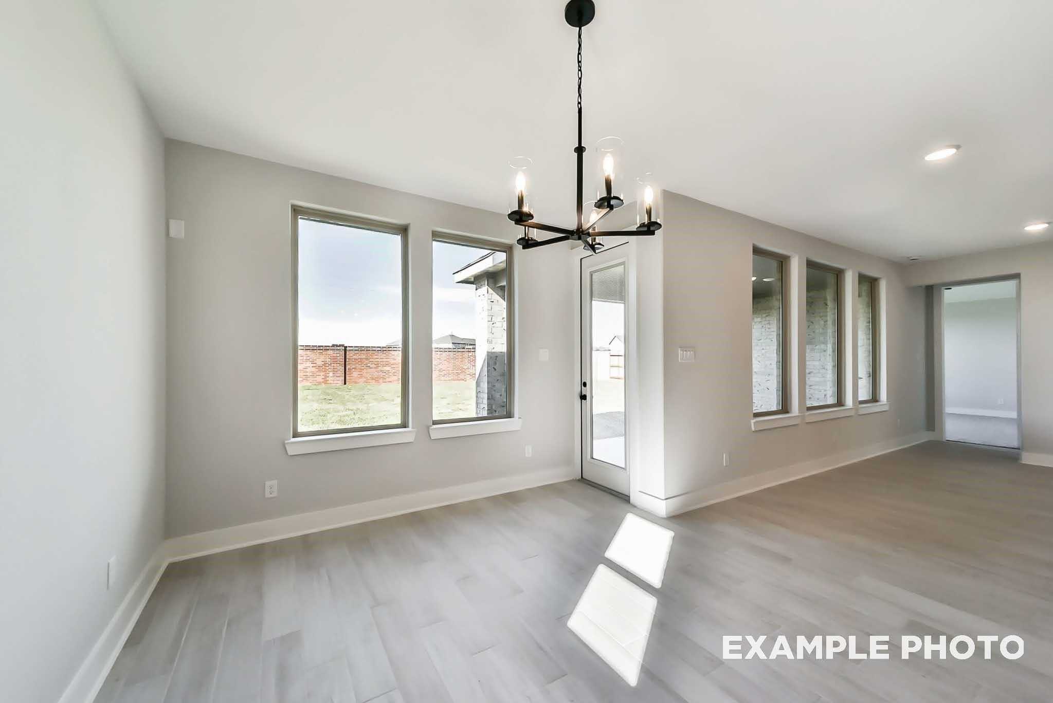 Sunlit dining area with black chandelier, large windows, and open layout in 4-bedroom Davidson Homes The Philip C, Rosharon, Texas