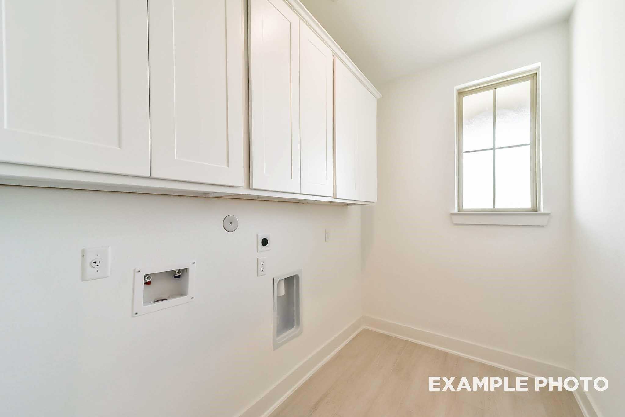 Bright laundry room featuring white cabinets, washer/dryer hookups, and window in Davidson Homes The Philip C, Rosharon, Texas