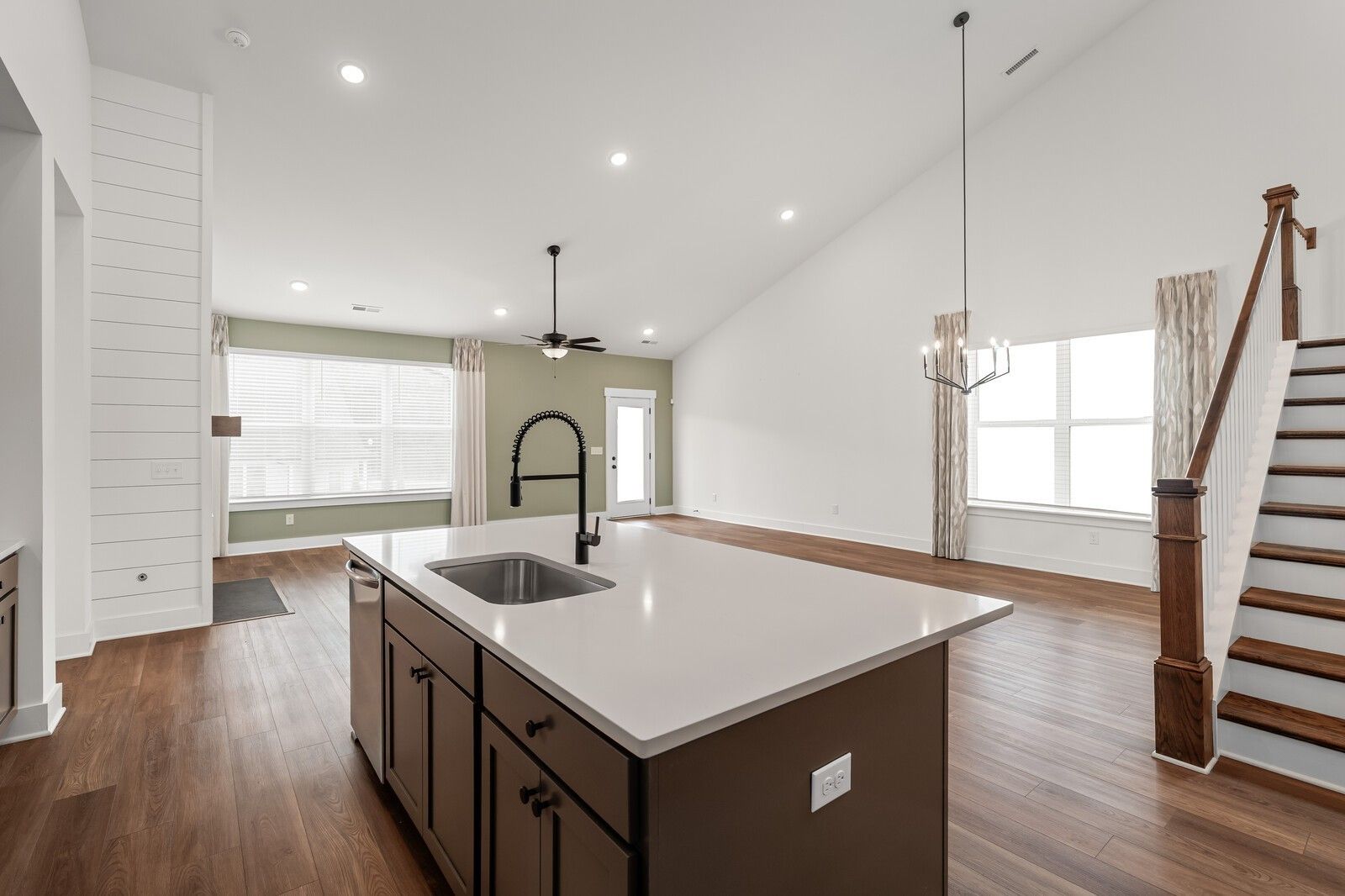 Open-concept kitchen with large island, white quartz counters, dark cabinets, and gooseneck faucet in The Ridgeport by Davidson Homes, Gallatin TN
